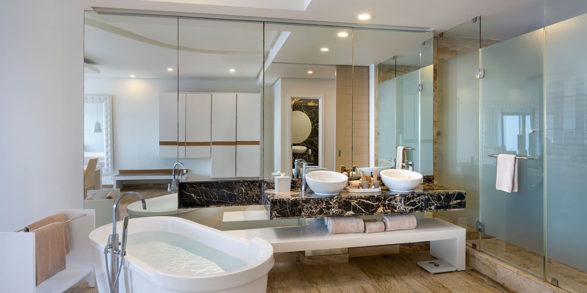a bathroom with a large glass shower and a tub