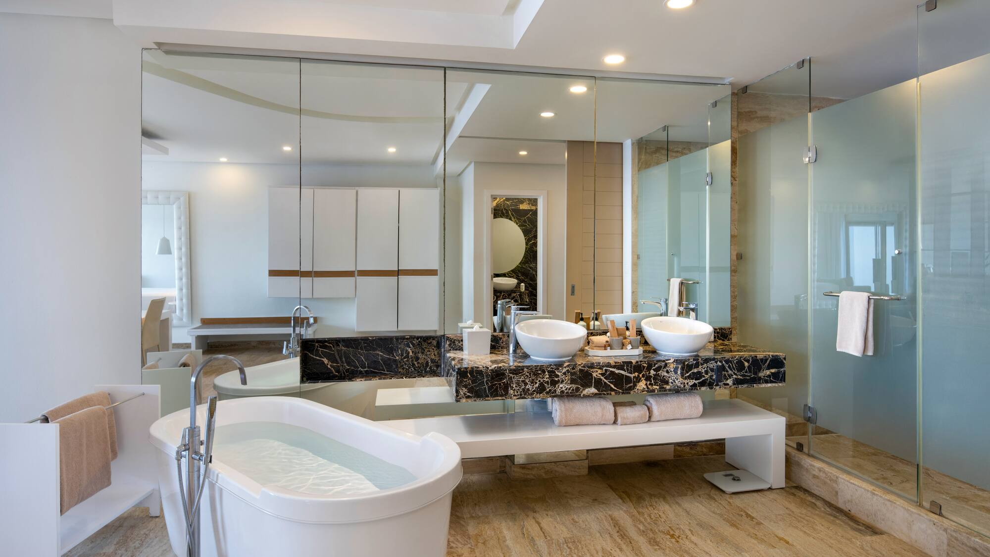 a bathroom with a large glass shower and a tub