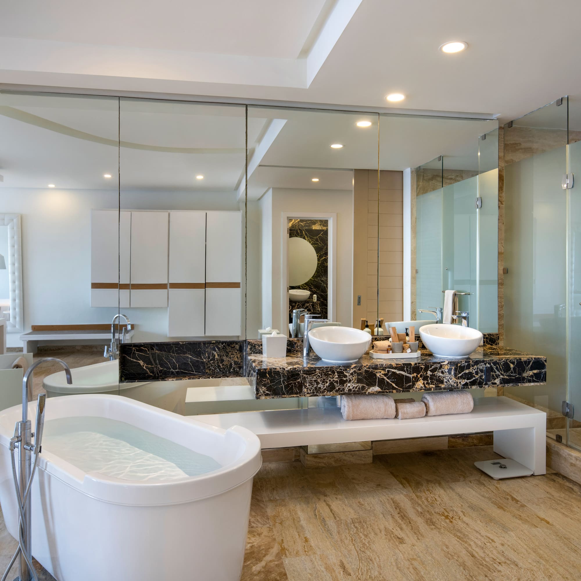 a bathroom with a large glass shower and a tub