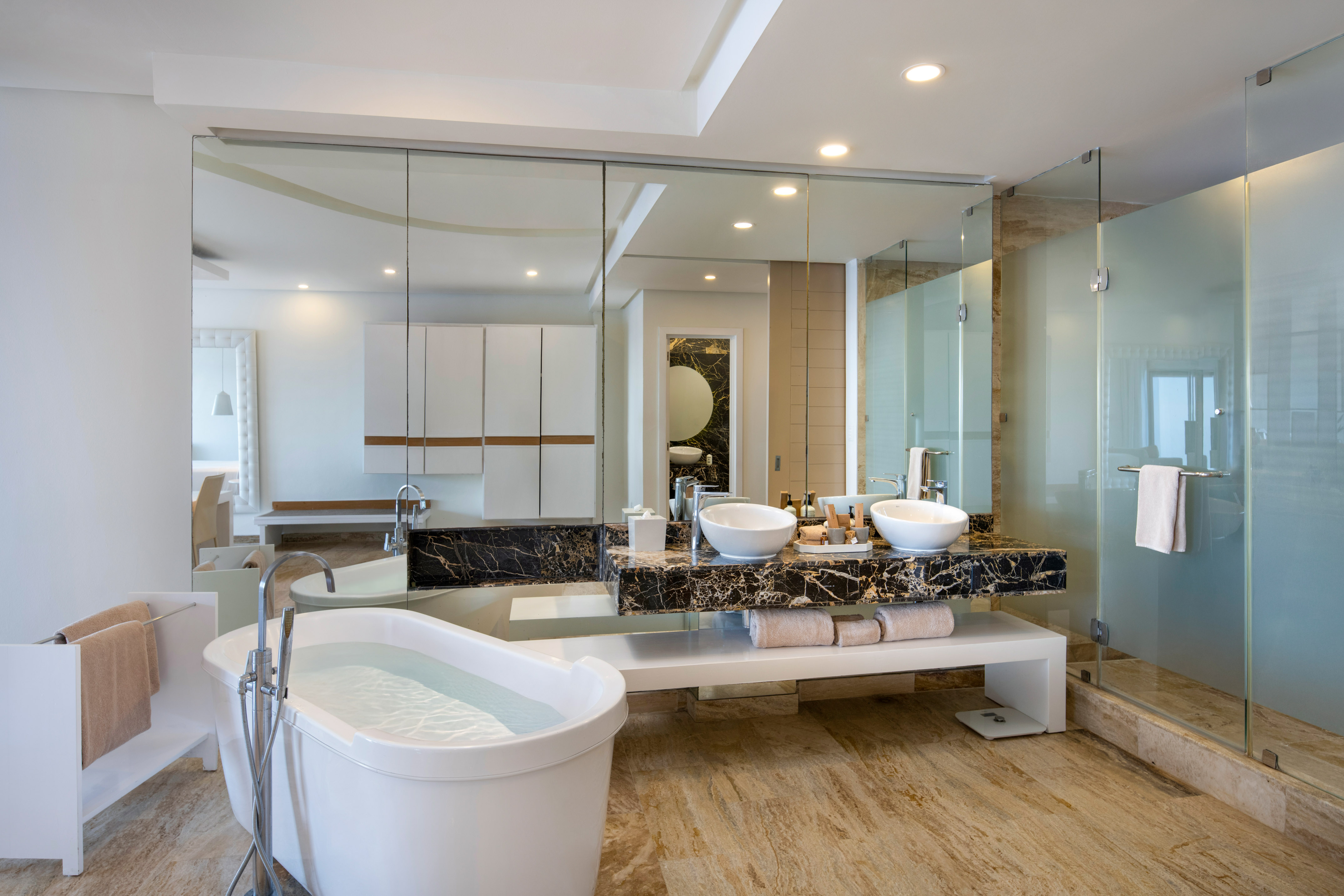 a bathroom with a large glass shower and a tub