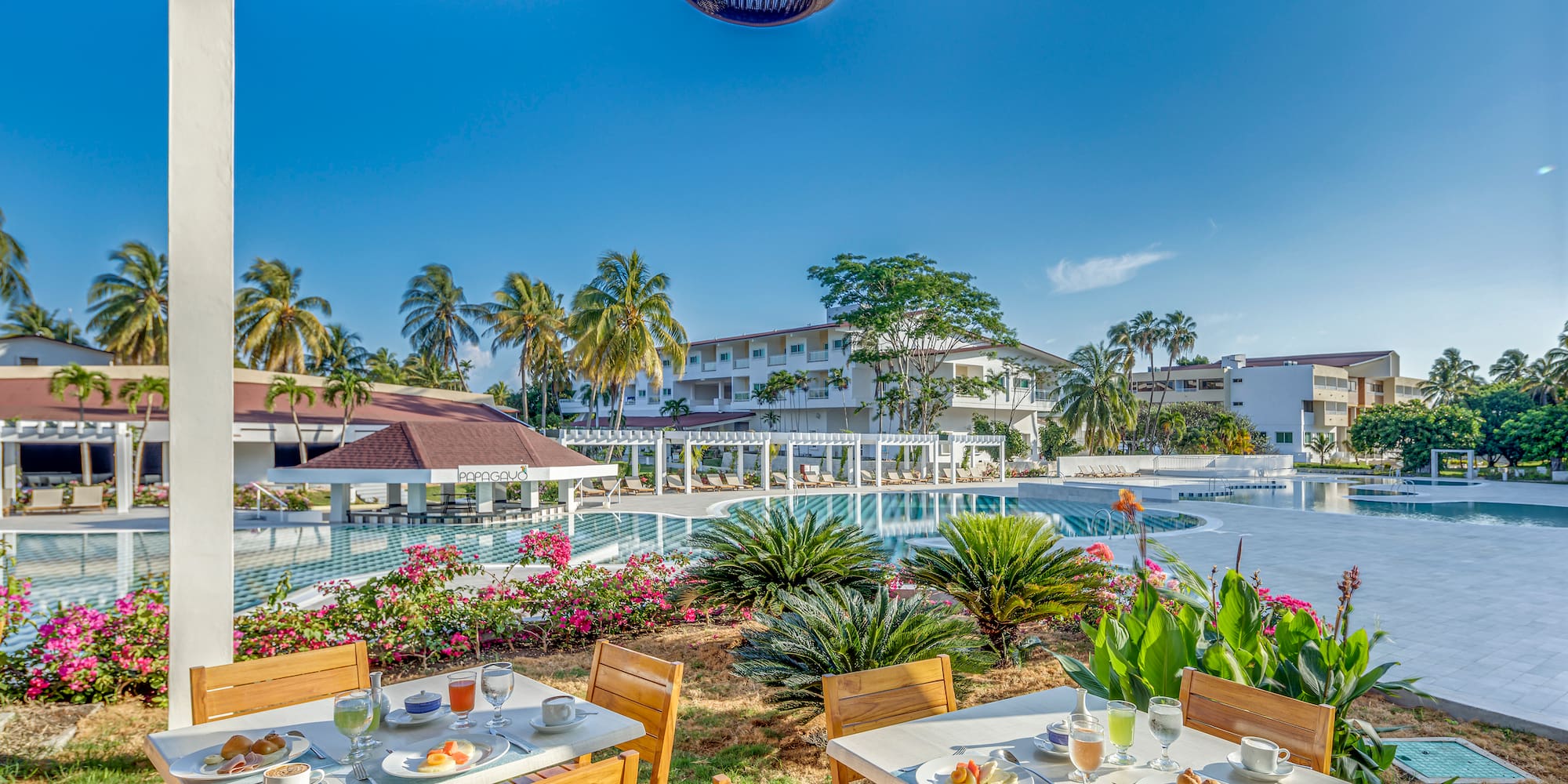 a table and chairs with food on it by a pool