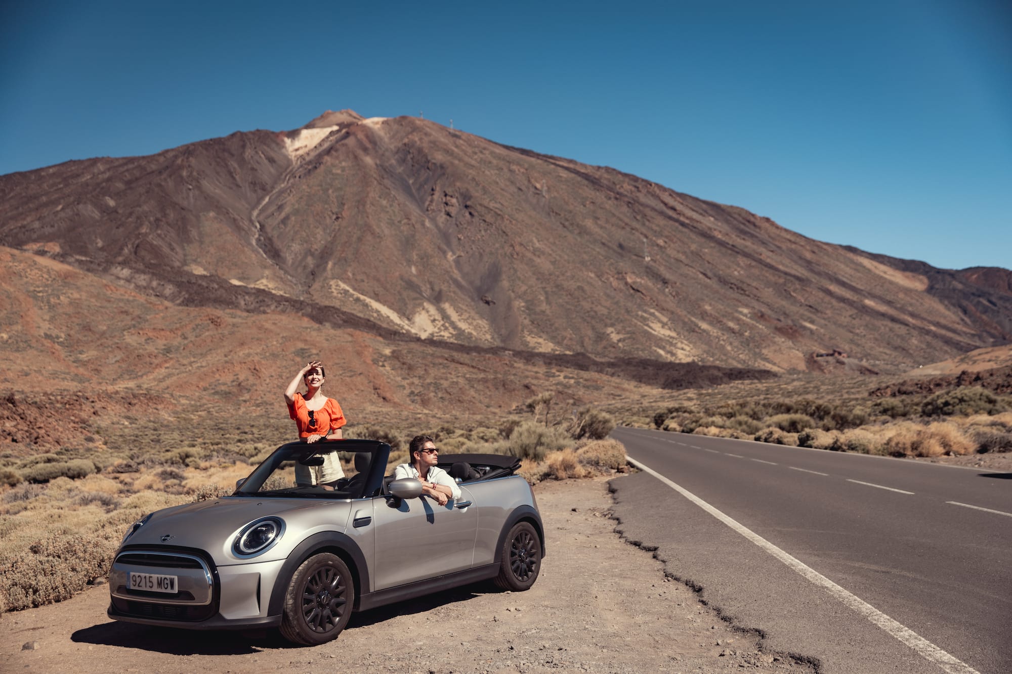 Pareja en Mini Cooper descapotable frente al volcán Teide, Islas Canarias.