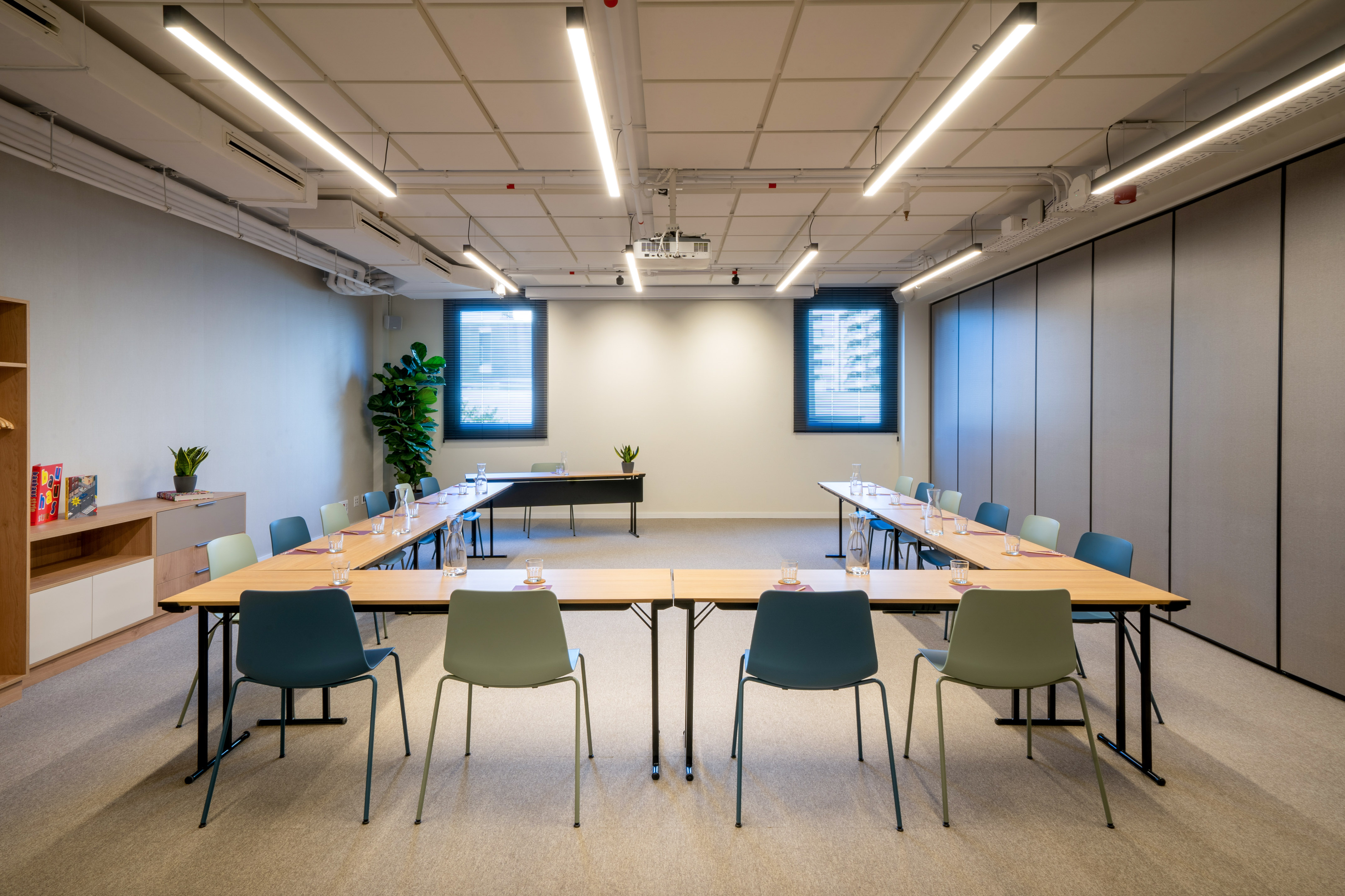 Modern conference room with tables, chairs, projector, and bright lighting.