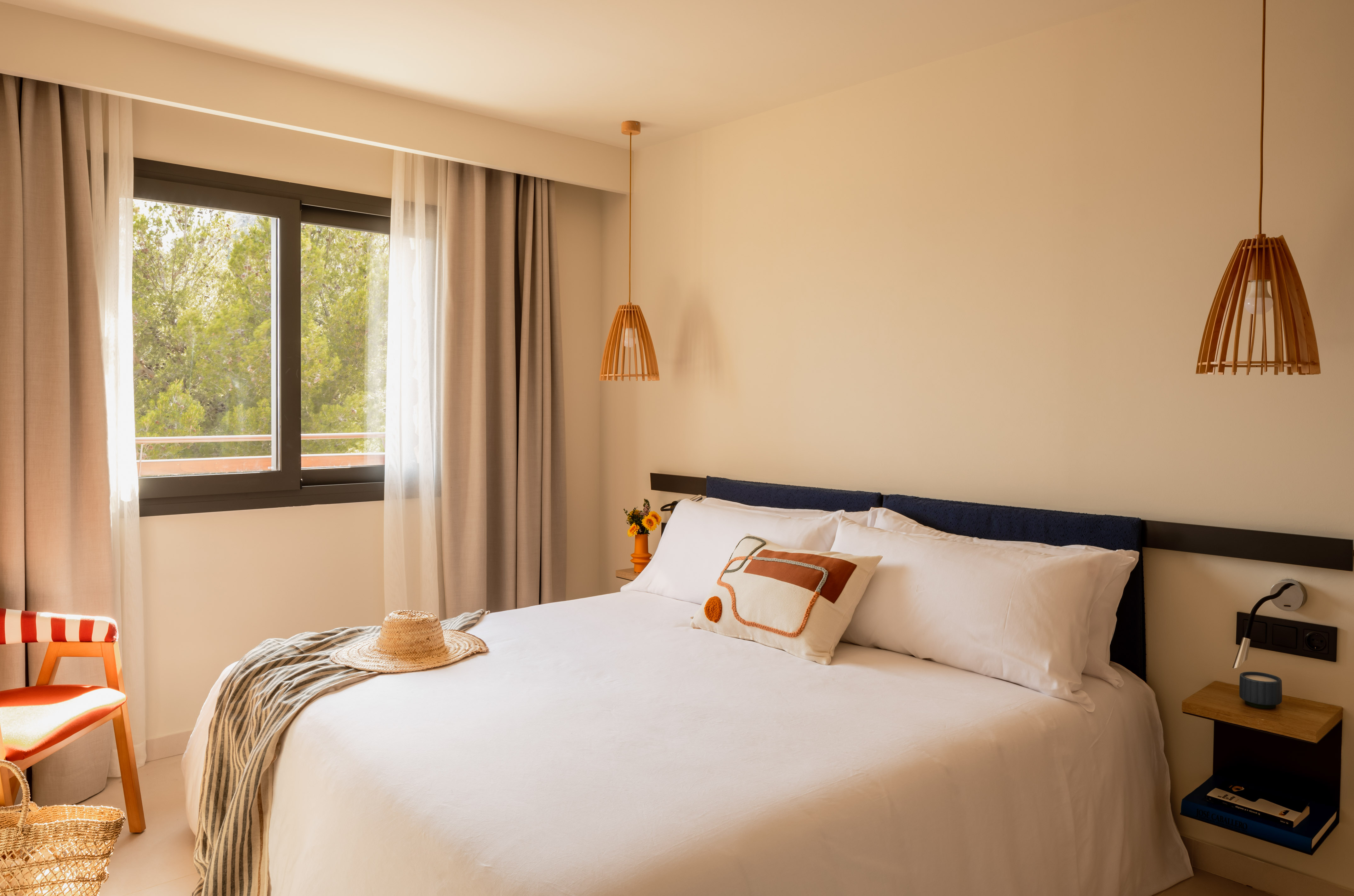 Cozy modern bedroom with white bed, nature view window, and minimalist wood accents.