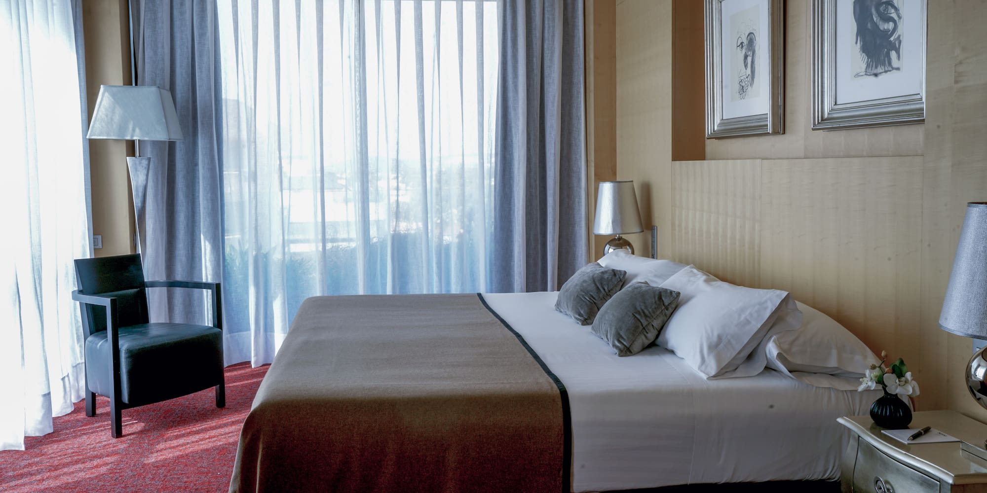 a bed with pillows and a chair in a room with curtains