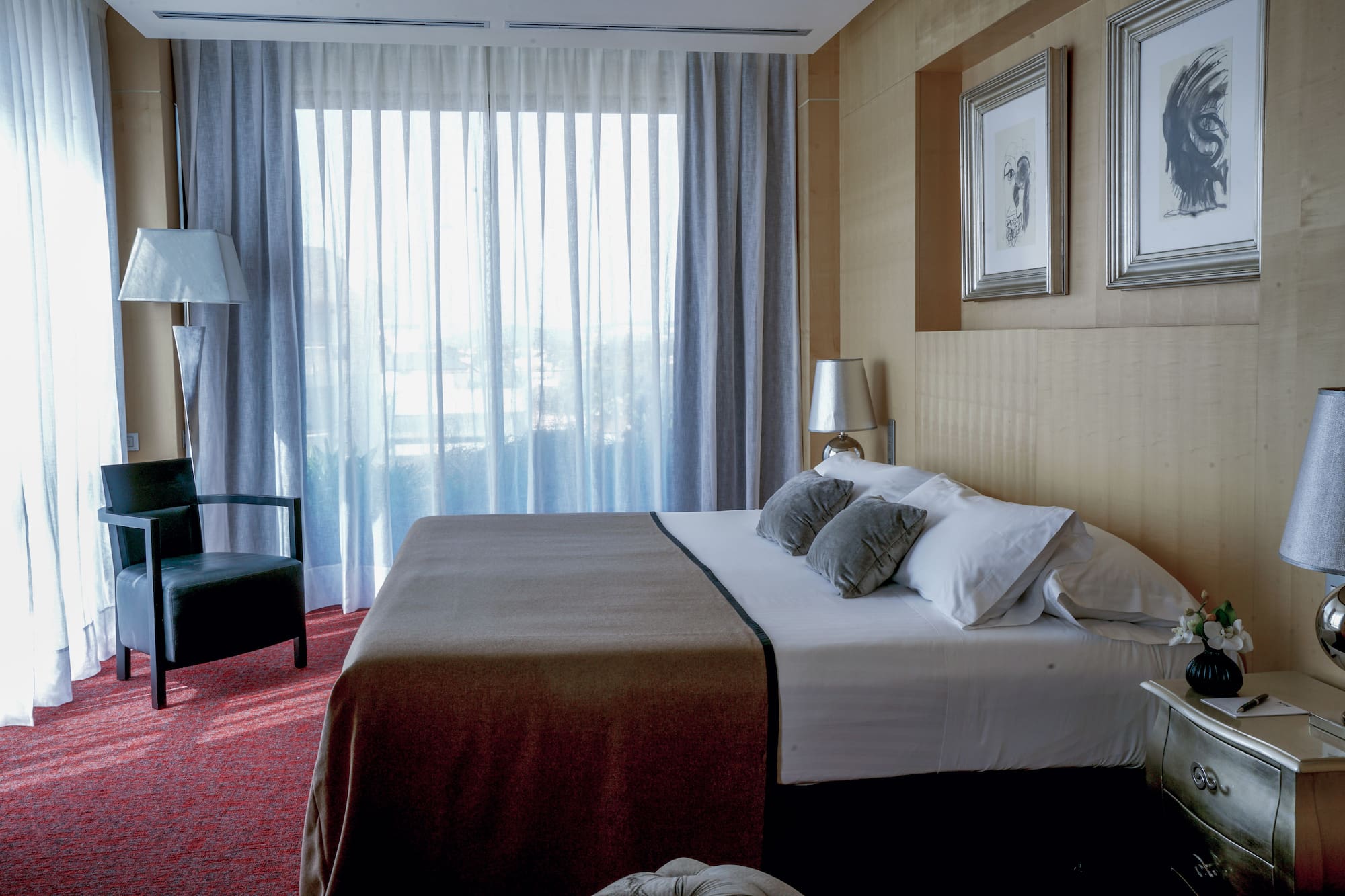 a bed with pillows and a chair in a room with curtains