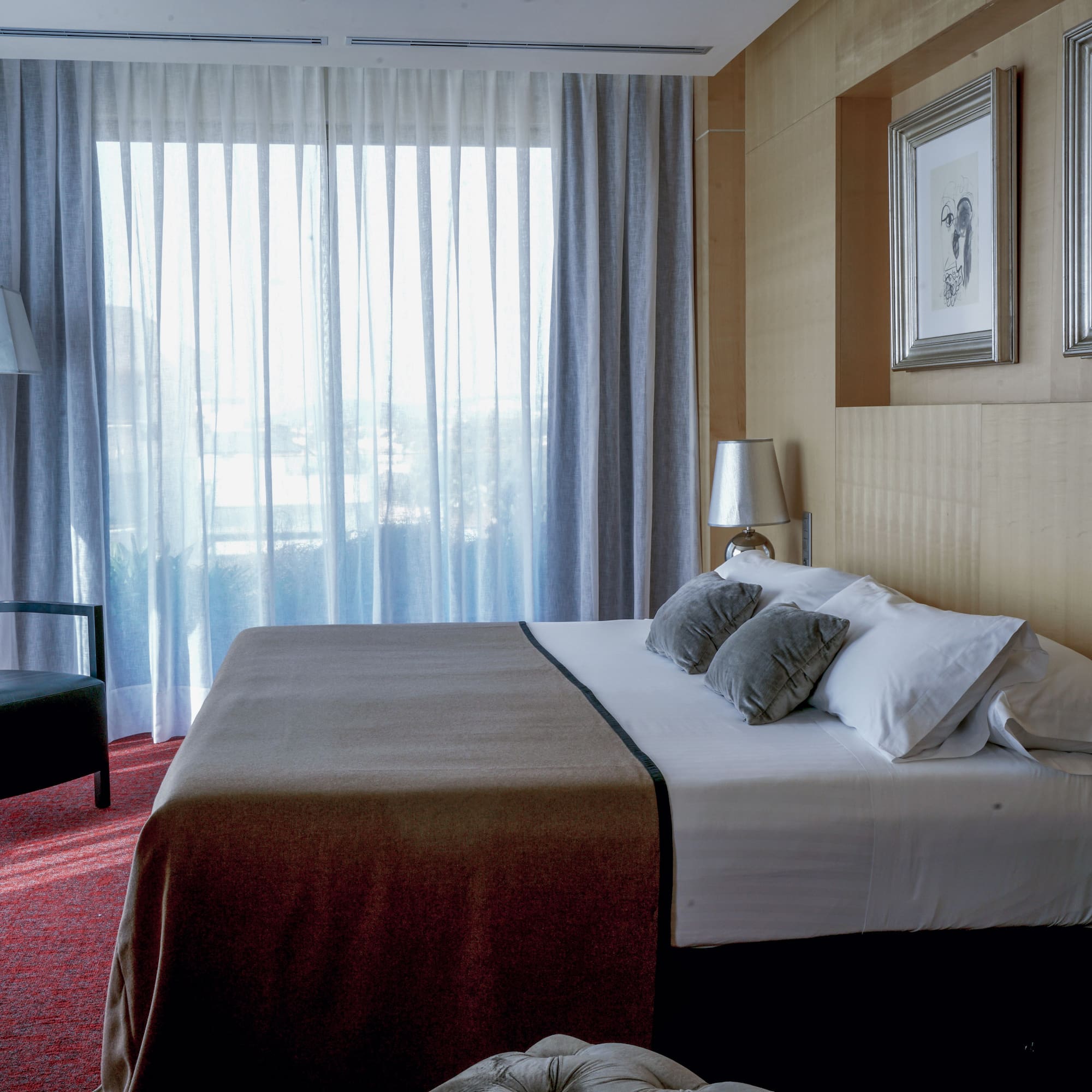 a bed with pillows and a chair in a room with curtains