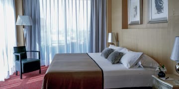 a bed with pillows and a chair in a room with curtains