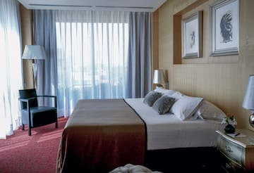 a bed with pillows and a chair in a room with curtains