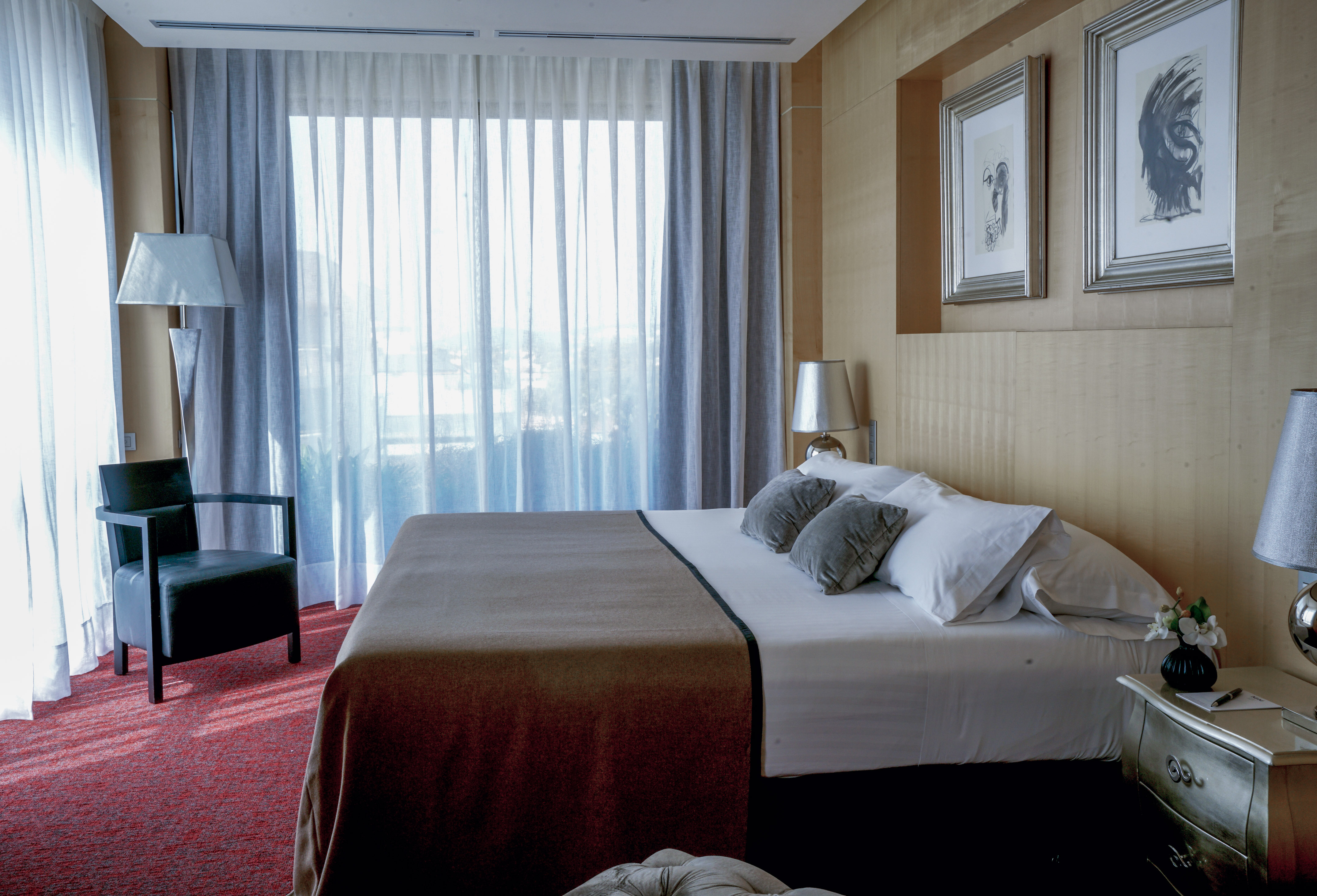 a bed with pillows and a chair in a room with curtains