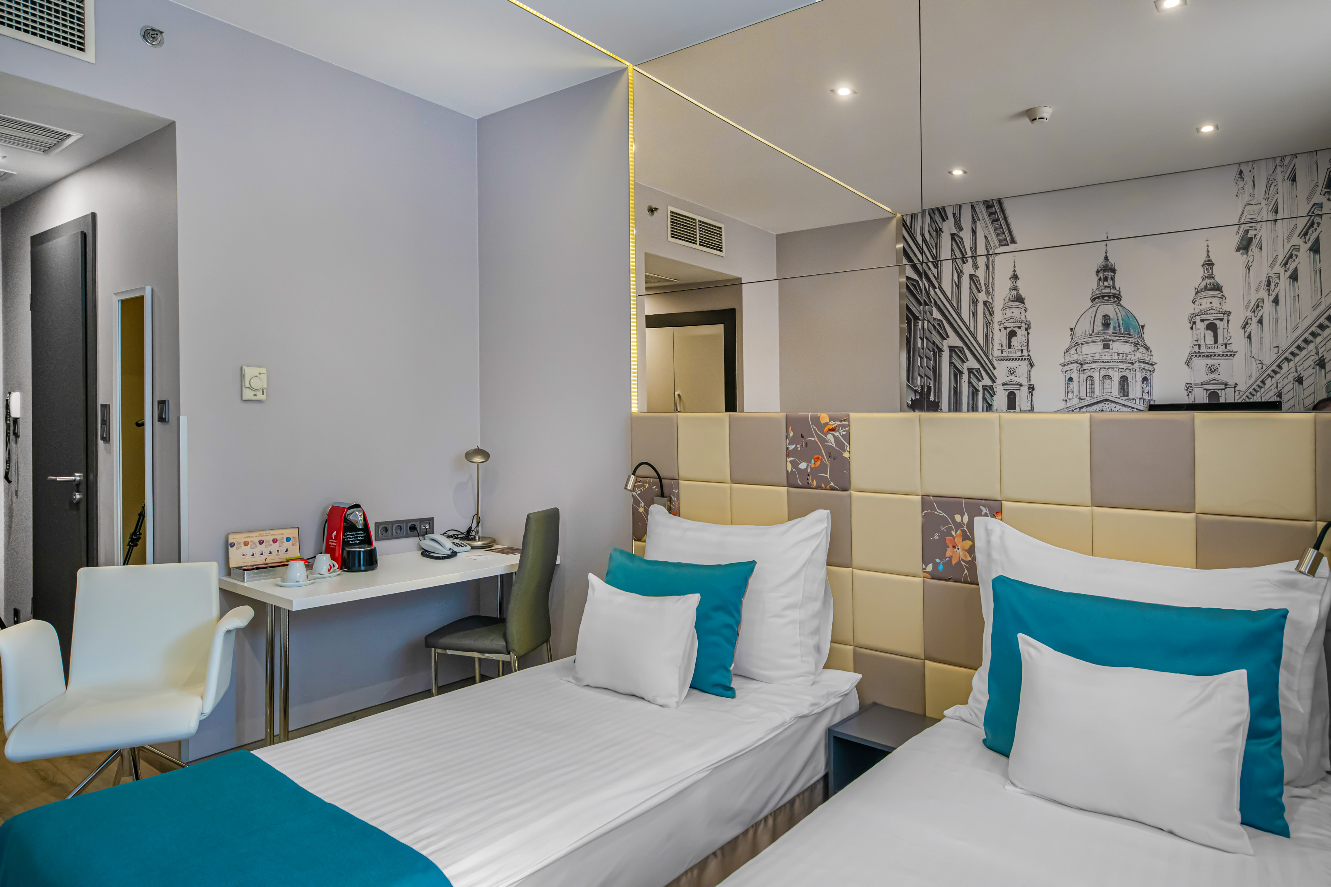Modern twin hotel room with two beds, desk, coffee maker, and urban mural art. - Standard - Hotel President Budapest Affiliated by Meliá, Budapest