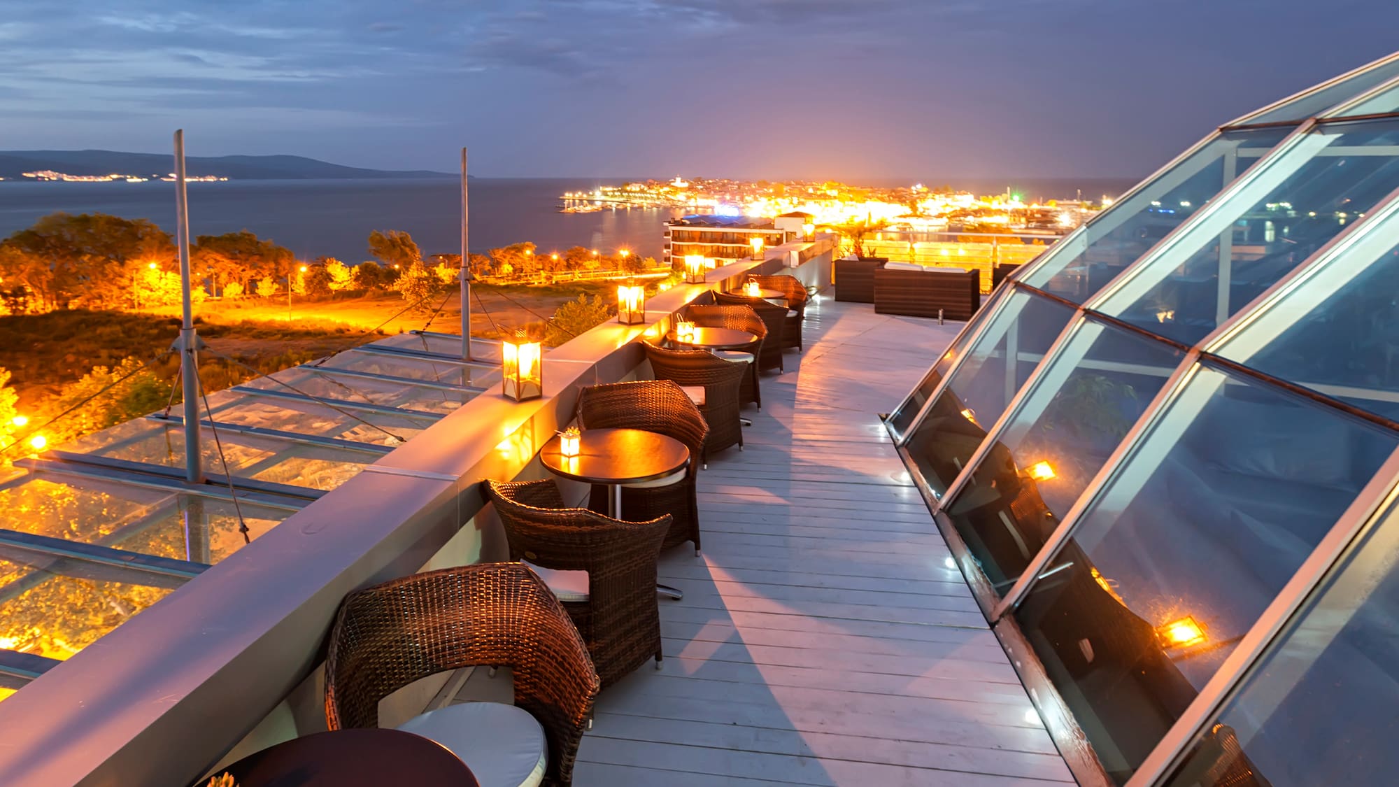 a rooftop with tables and chairs and a city in the background