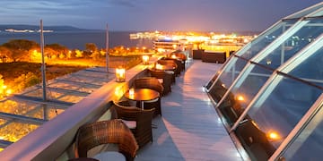 a rooftop with tables and chairs and a city in the background