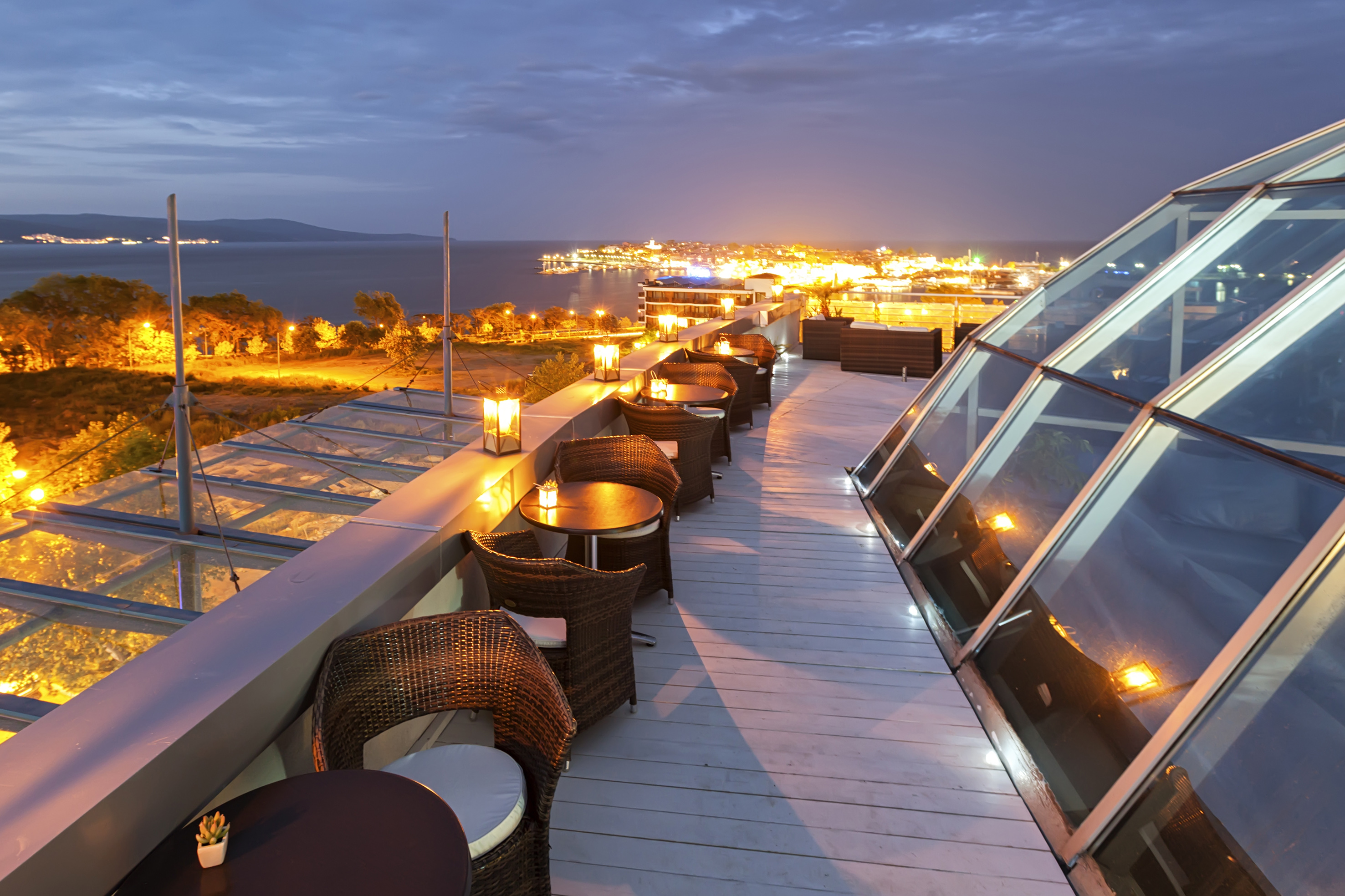a rooftop with tables and chairs and a city in the background