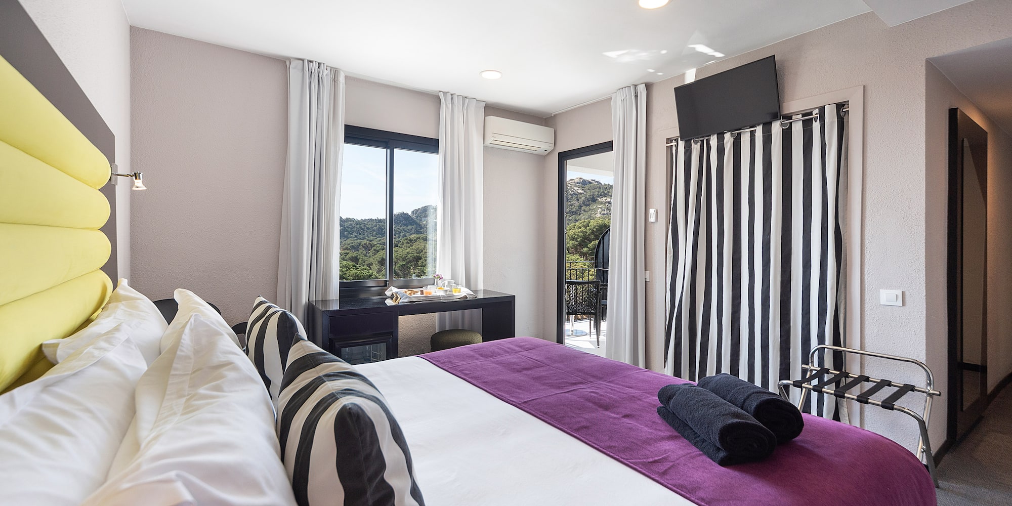 a bedroom with a purple bed and black and white striped curtains