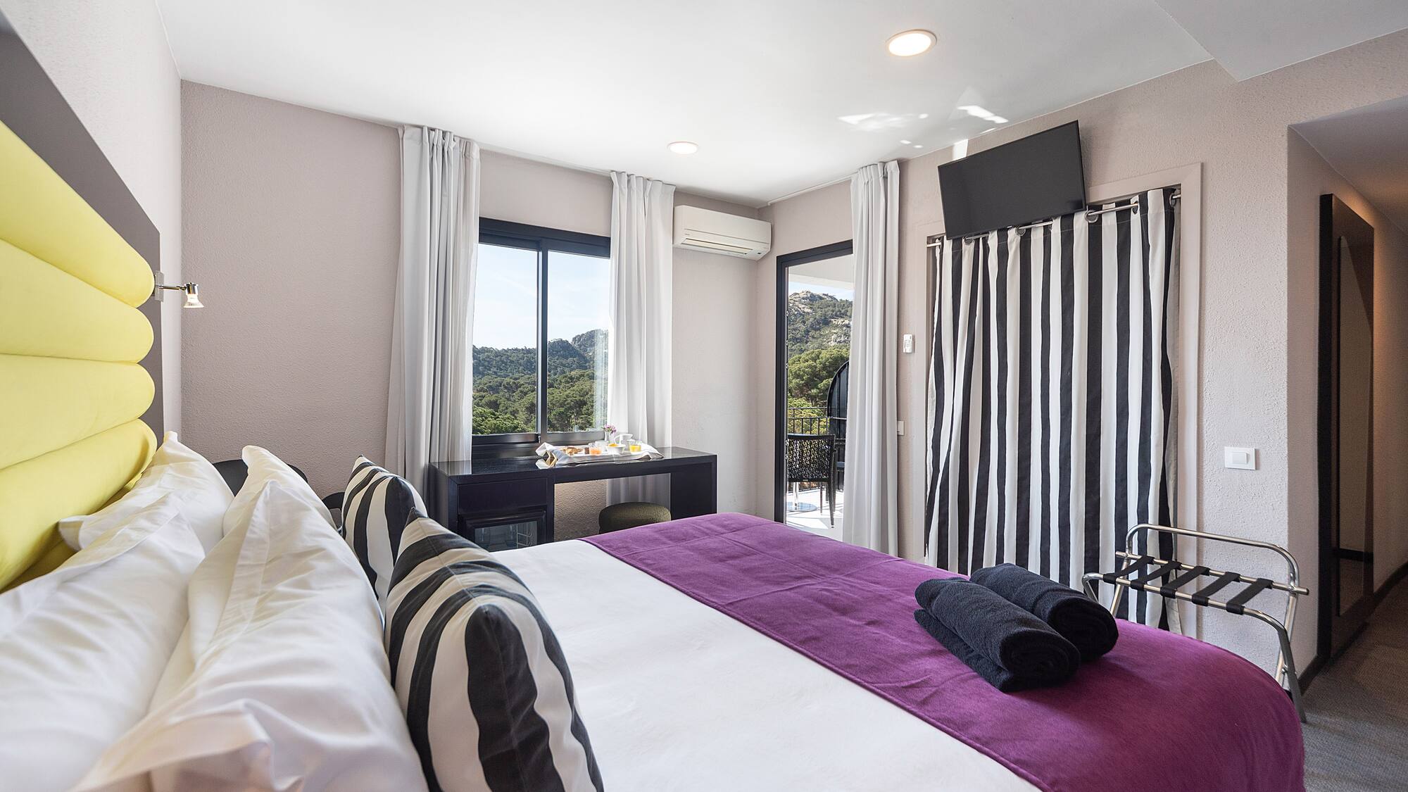 a bedroom with a purple bed and black and white striped curtains