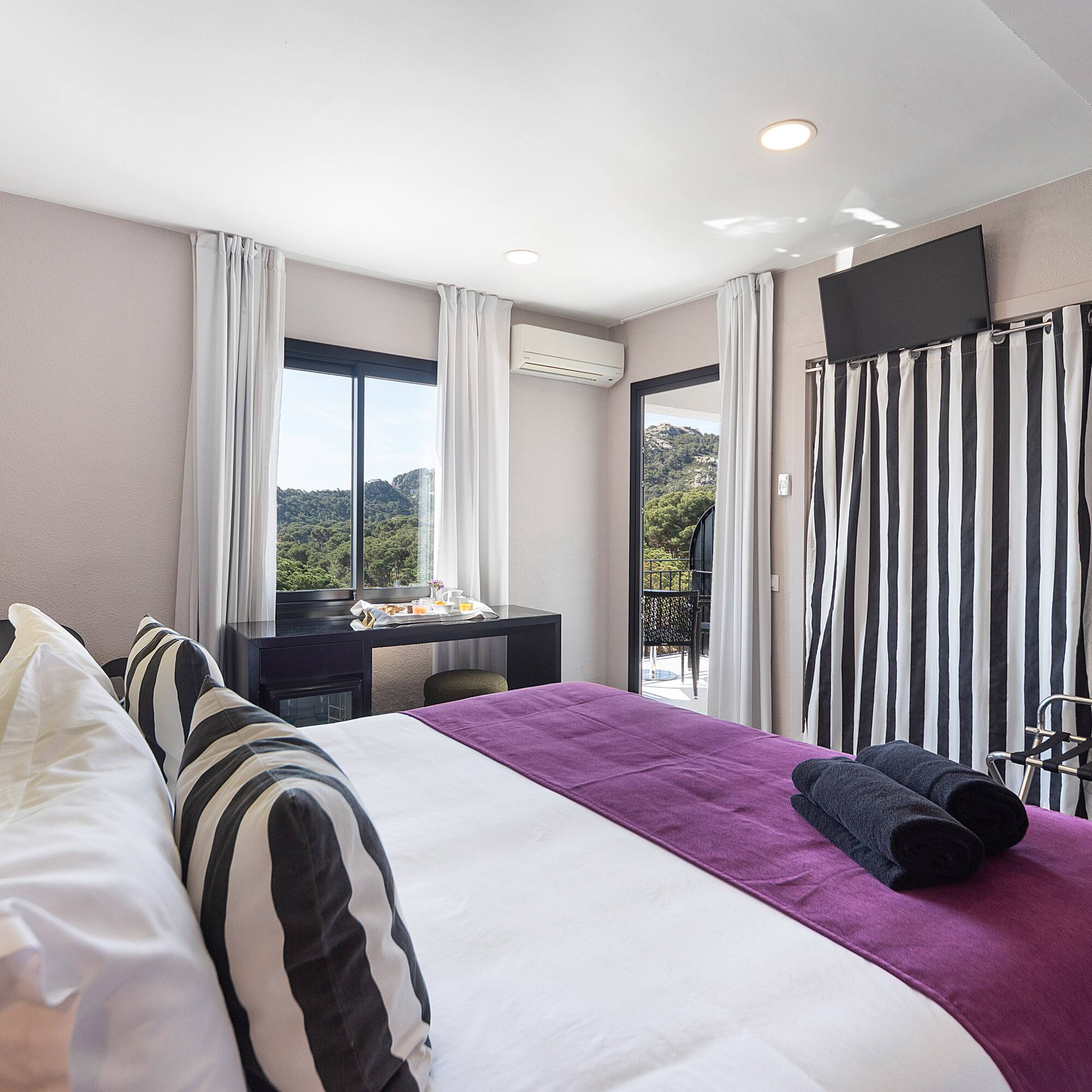 a bedroom with a purple bed and black and white striped curtains