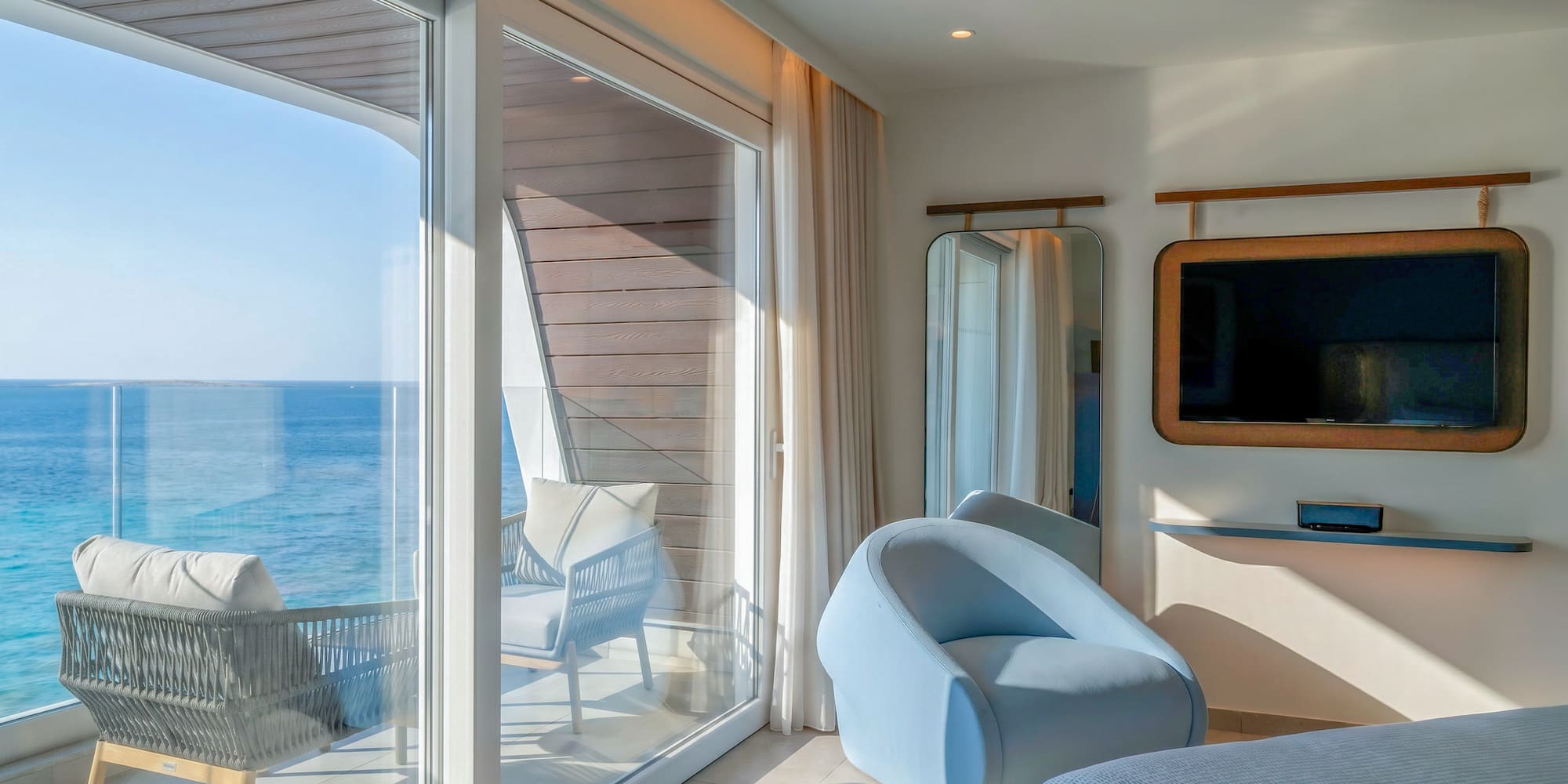 Modern hotel suite with ocean view balcony and contemporary interior.
