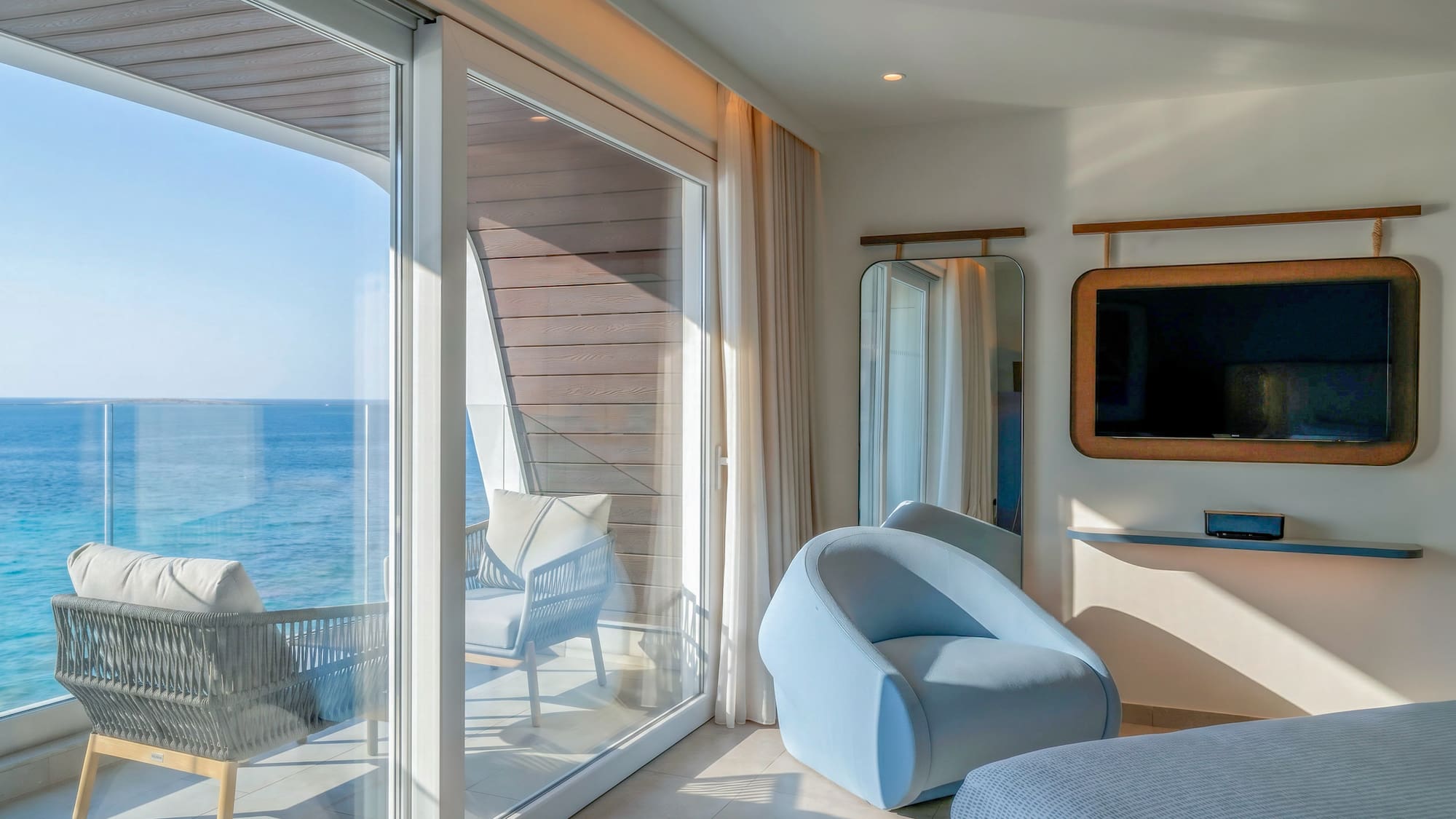 Modern hotel suite with ocean view balcony and contemporary interior.