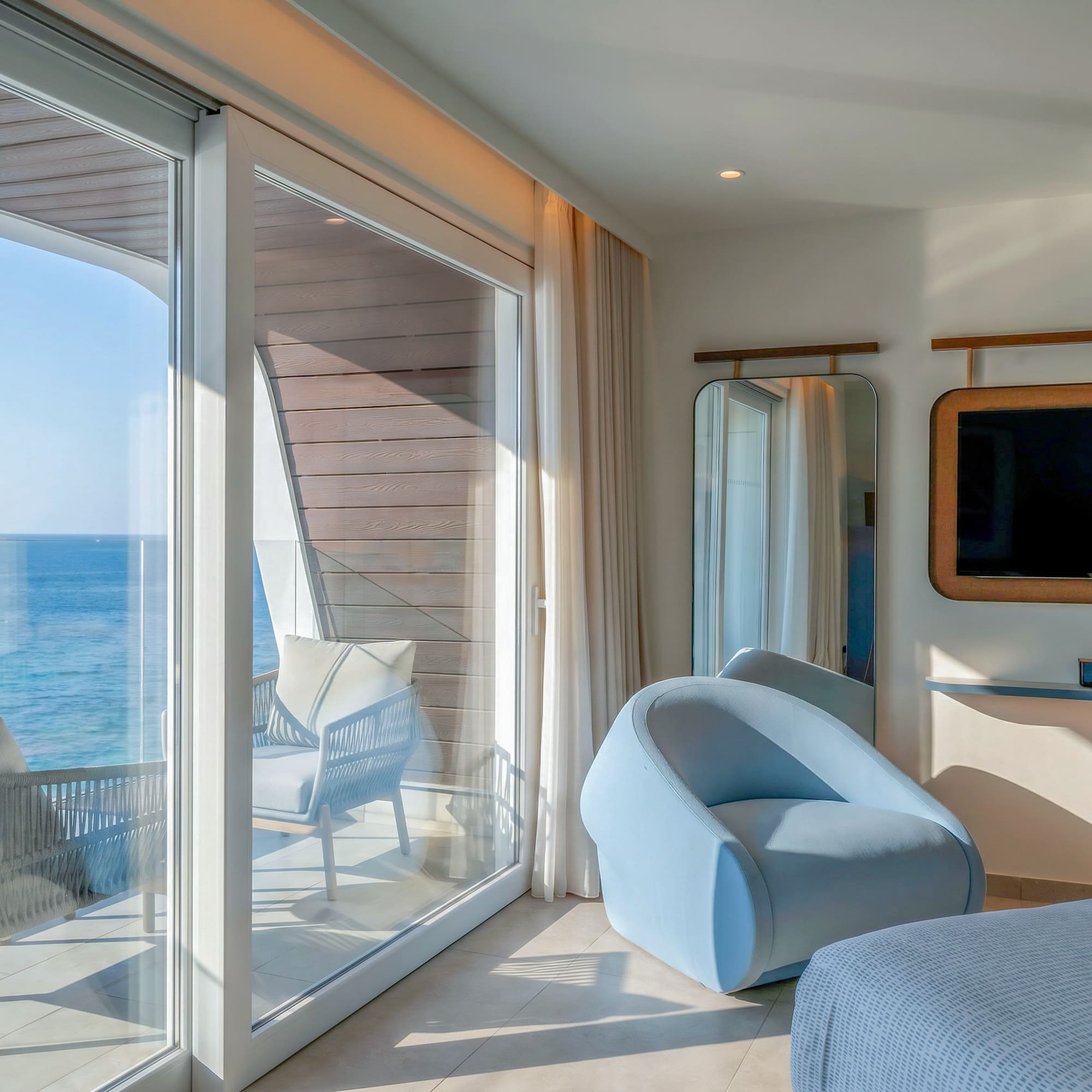 Modern hotel suite with ocean view balcony and contemporary interior.