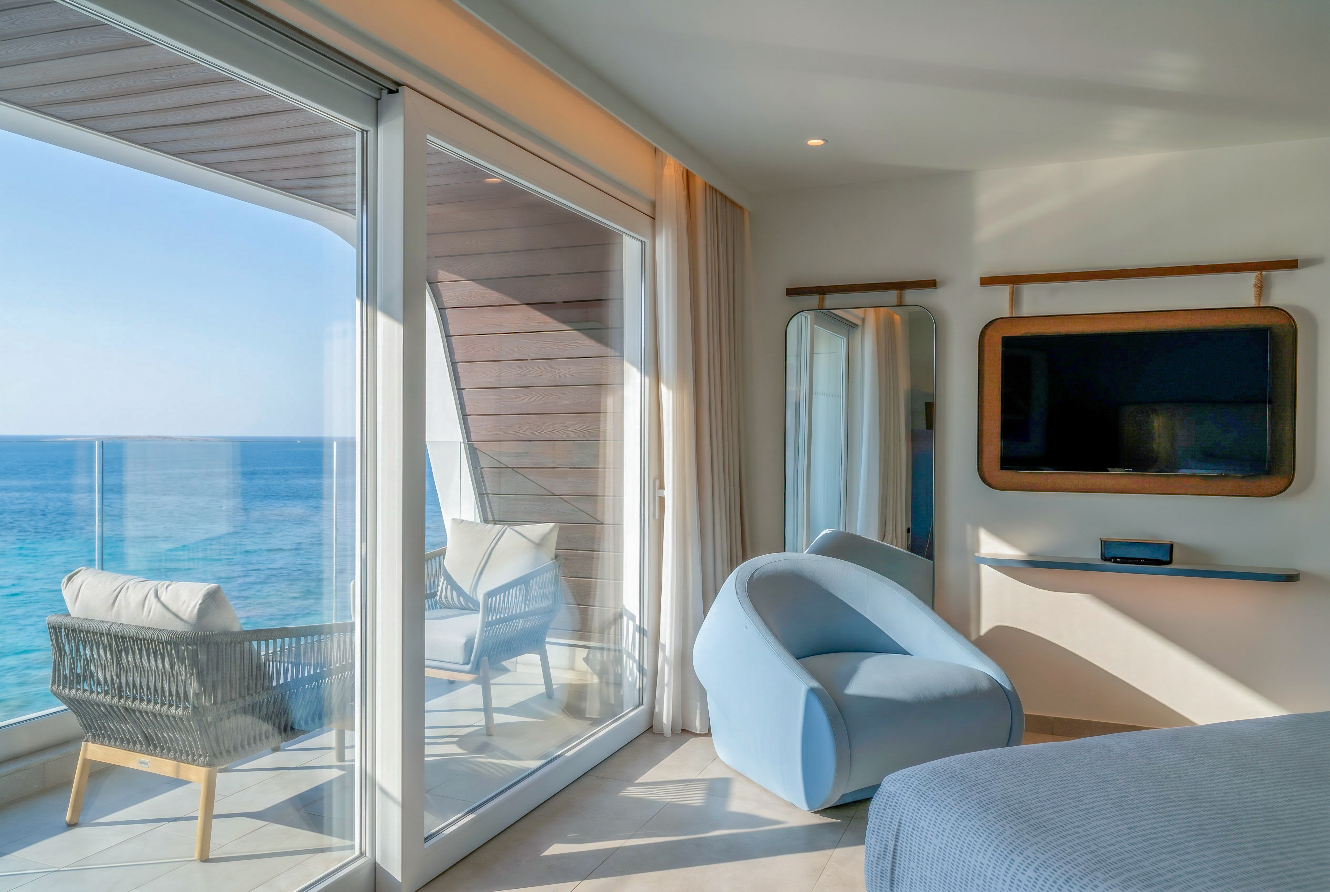 Modern hotel suite with ocean view balcony and contemporary interior.