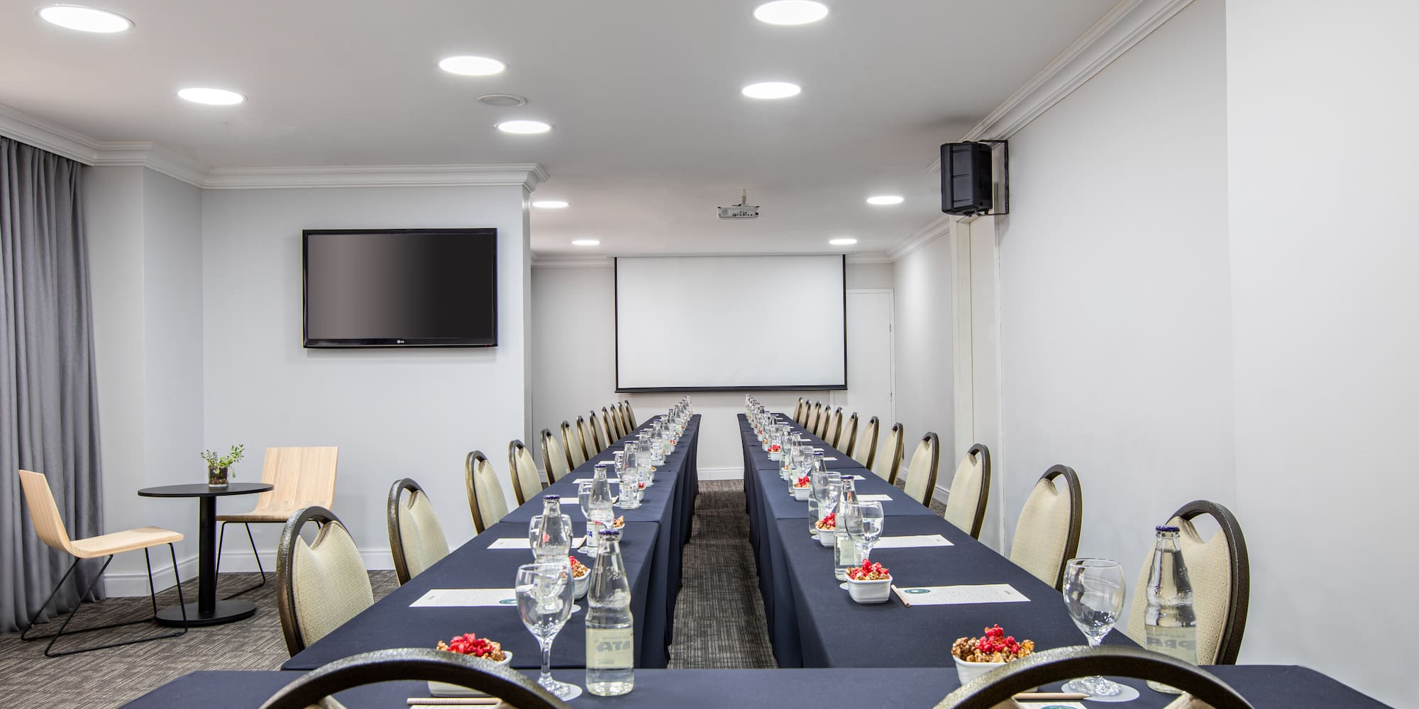 a long table with glasses and a screen in the background