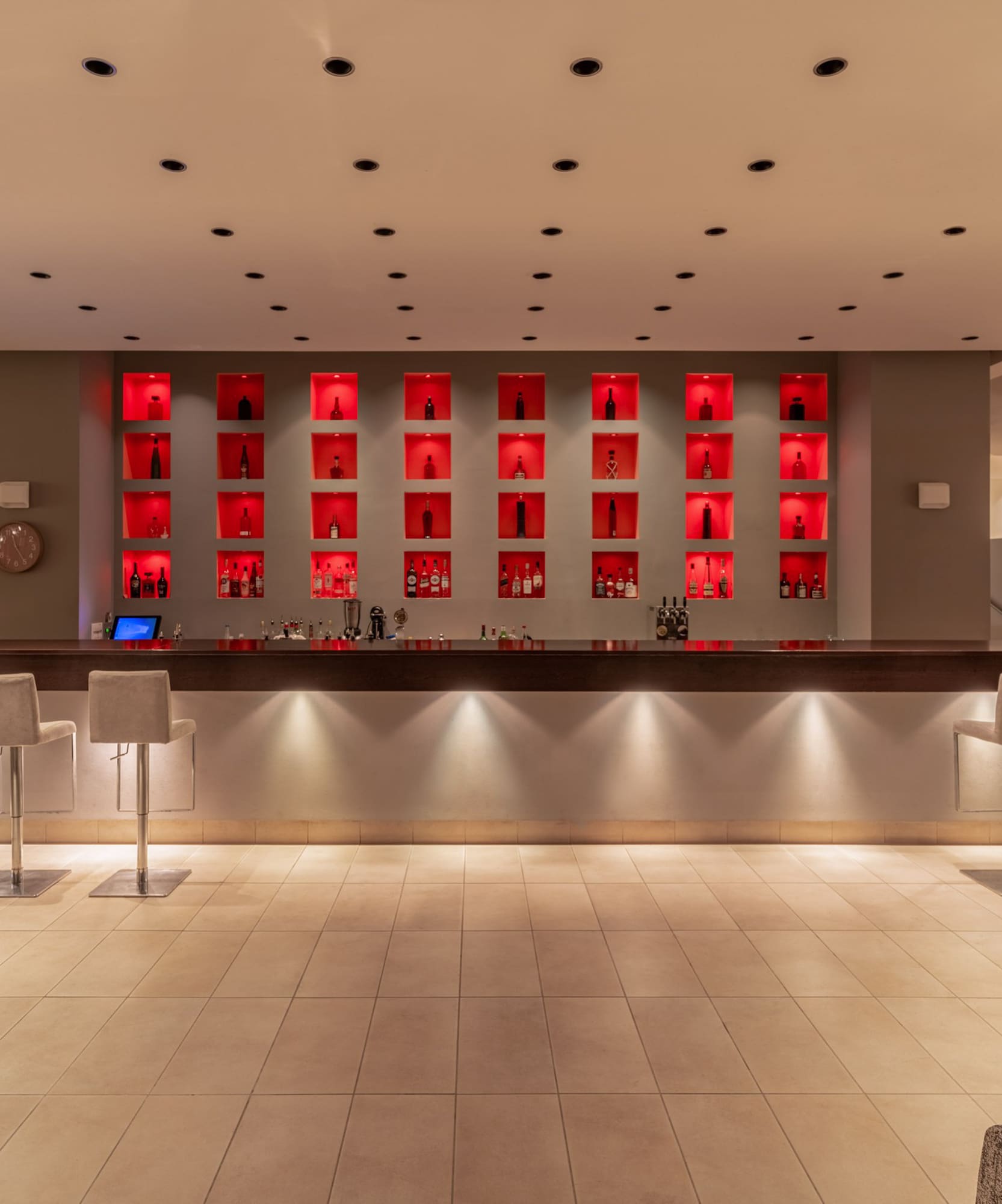 Sleek hotel bar with illuminated liquor display and comfortable seating.