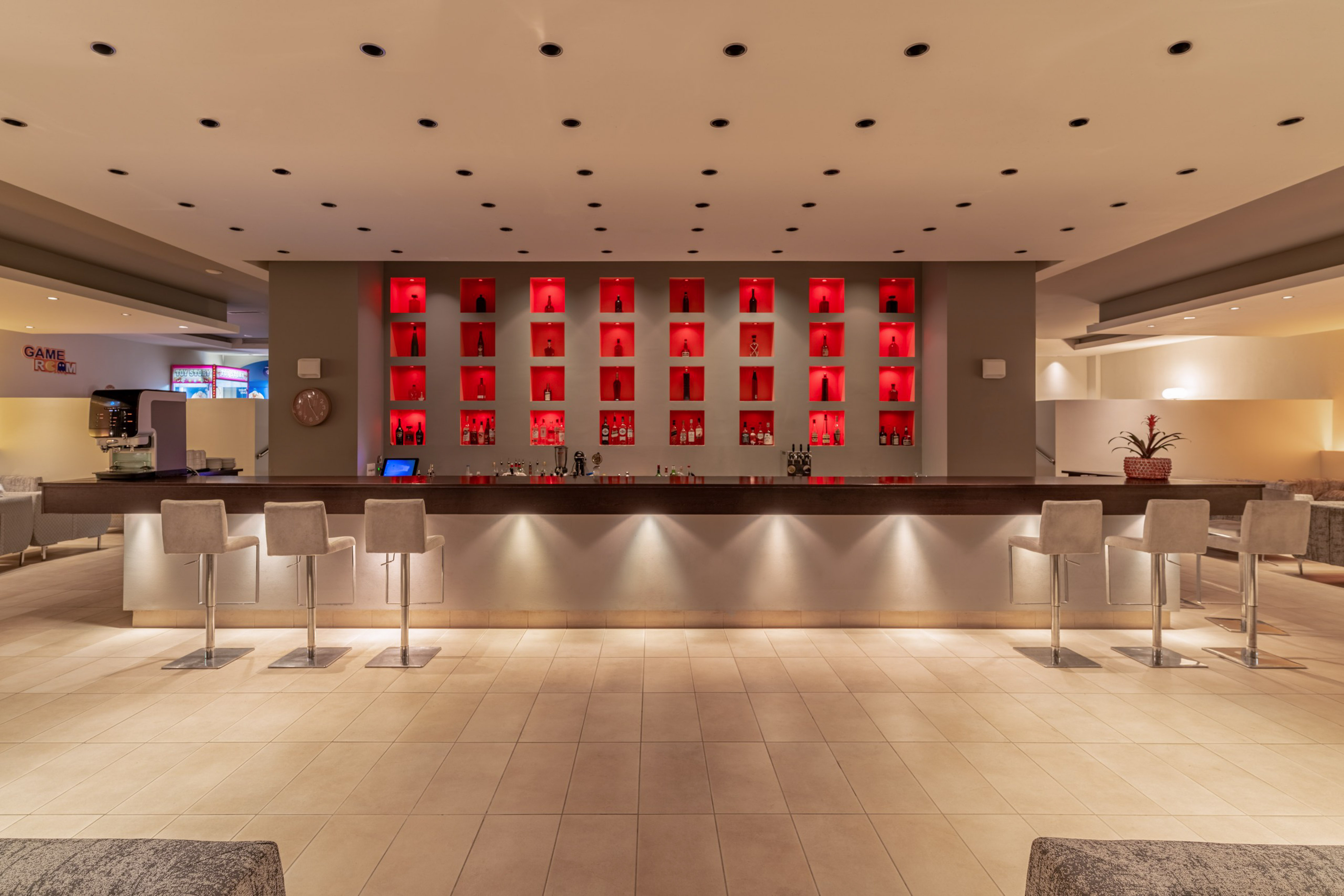 Sleek hotel bar with illuminated liquor display and comfortable seating.