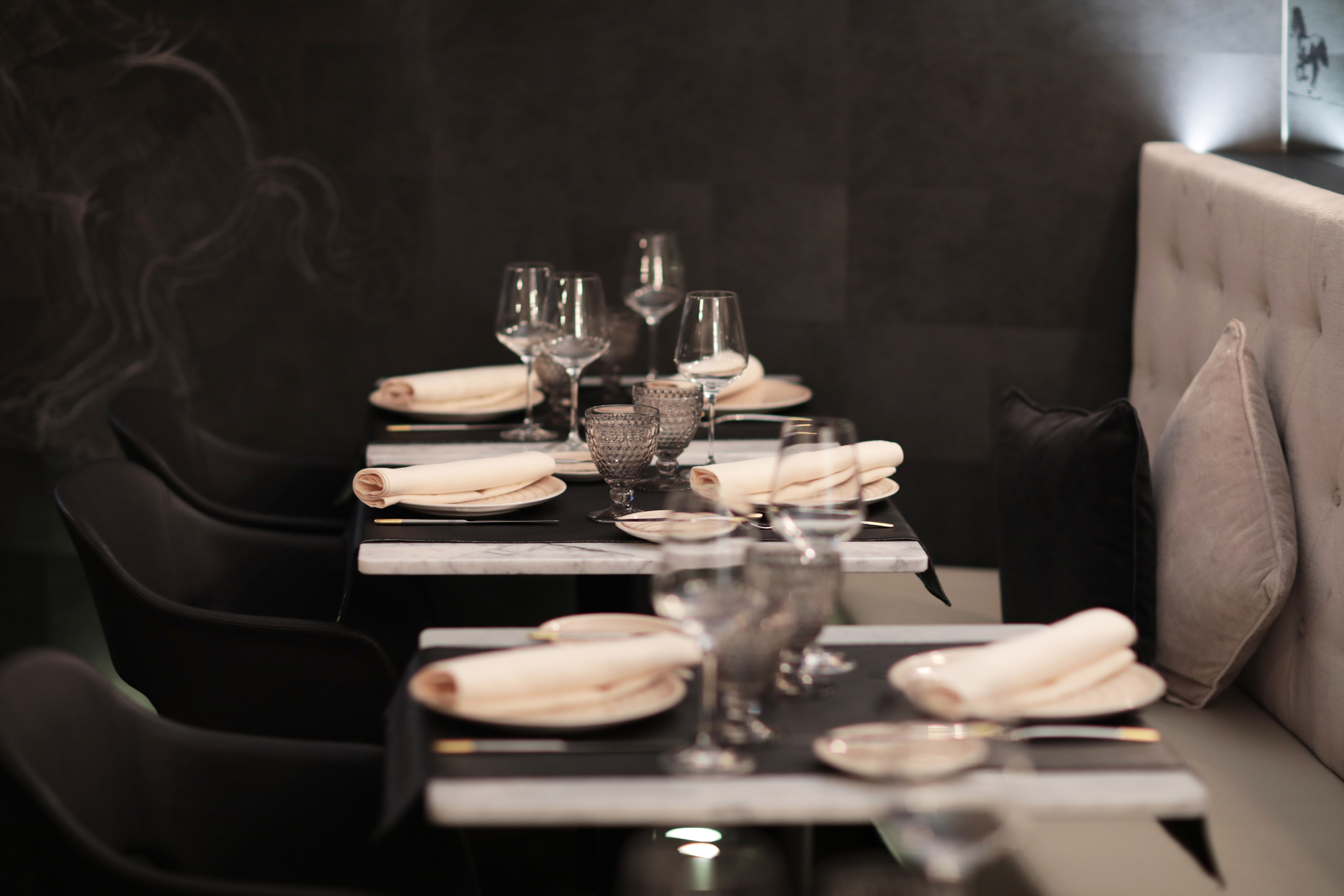 Elegant restaurant dining tables set with glassware, napkins, and modern chairs.