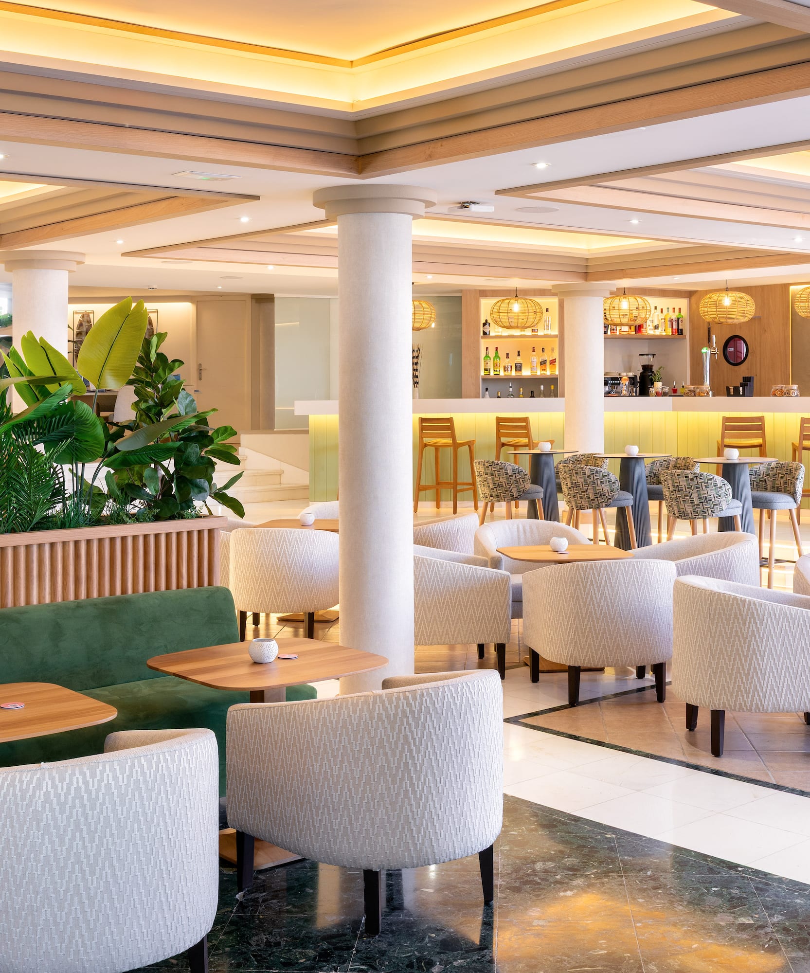 Stylish hotel bar with contemporary lounge seating and lush tropical plants.