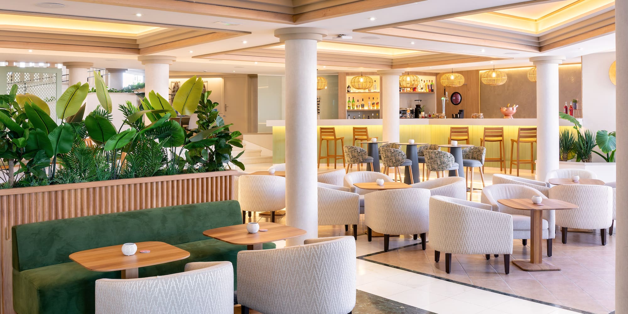 Modern hotel lounge bar with tropical plants and comfortable seating.