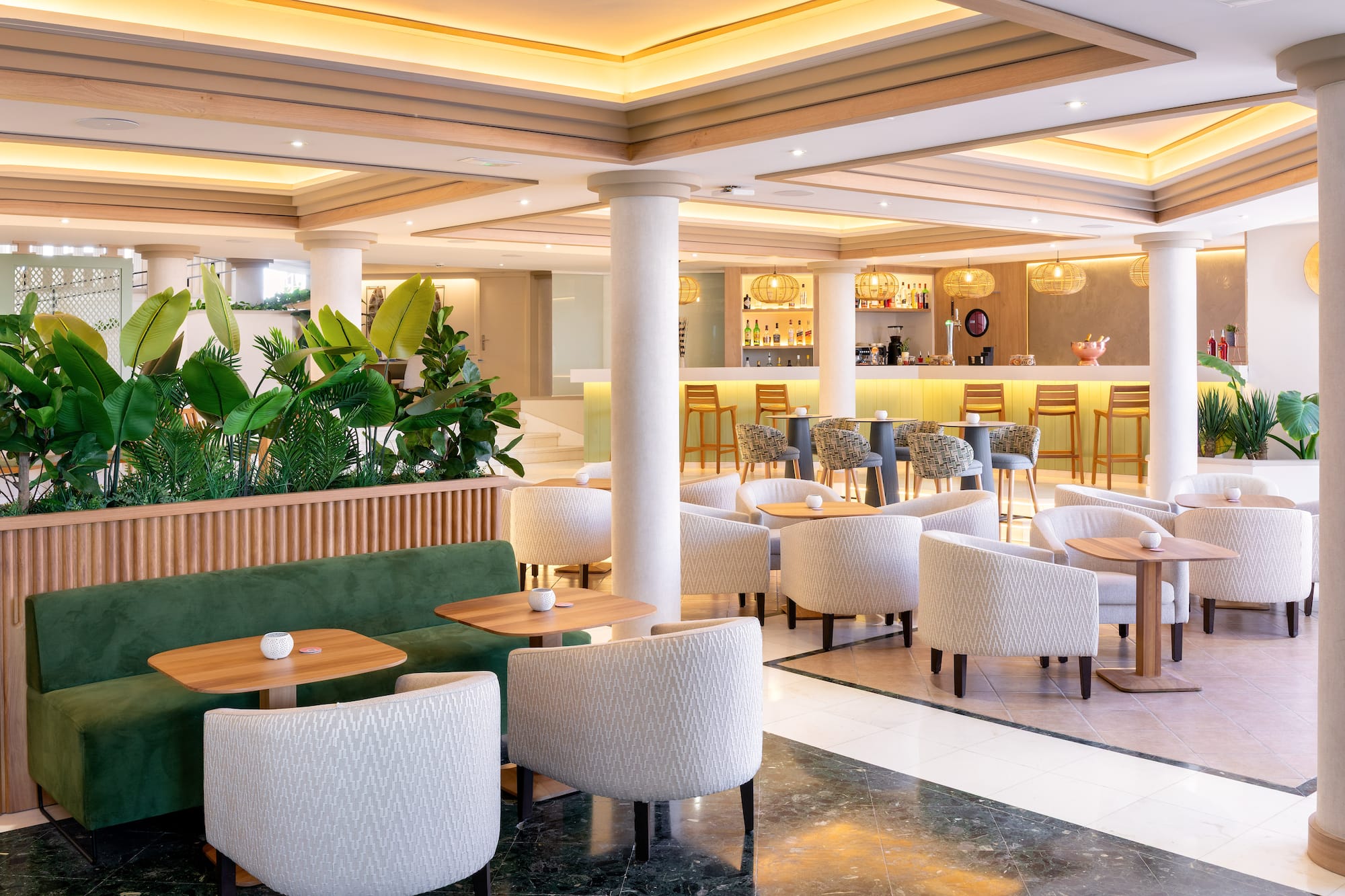 Modern hotel lounge bar with tropical plants and comfortable seating.