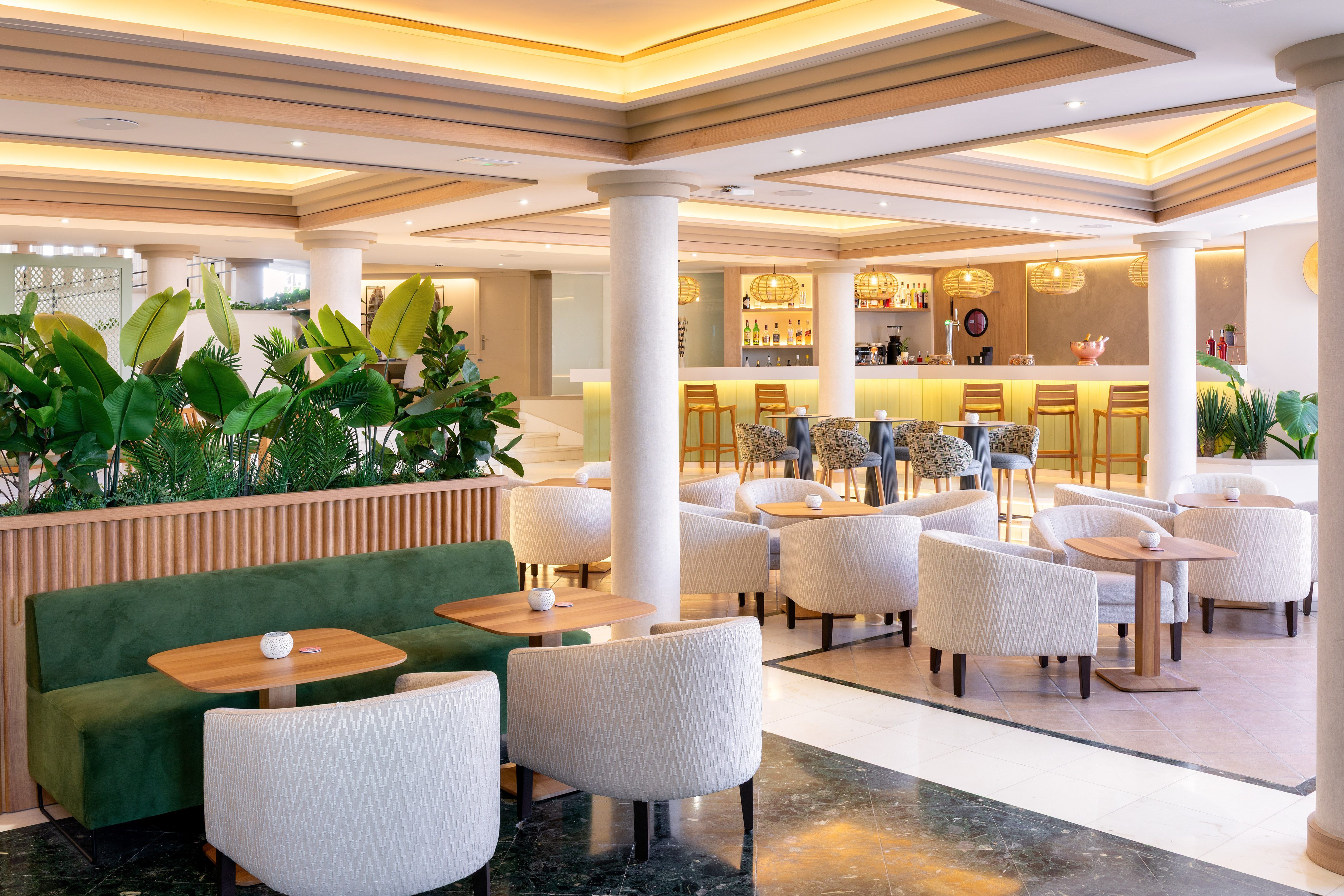 Modern hotel lounge bar with tropical plants and comfortable seating.