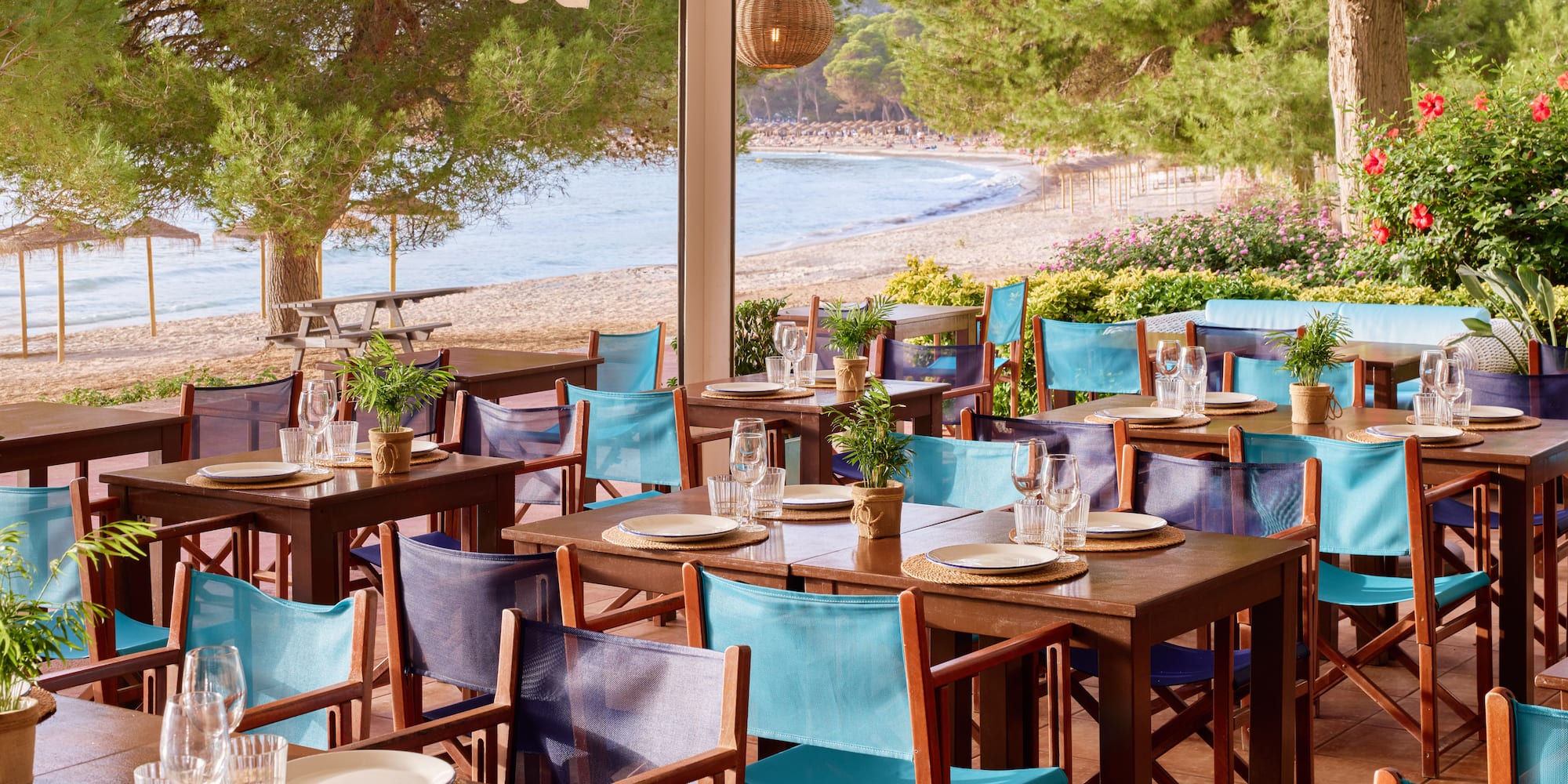 tables and chairs on a patio near a beach