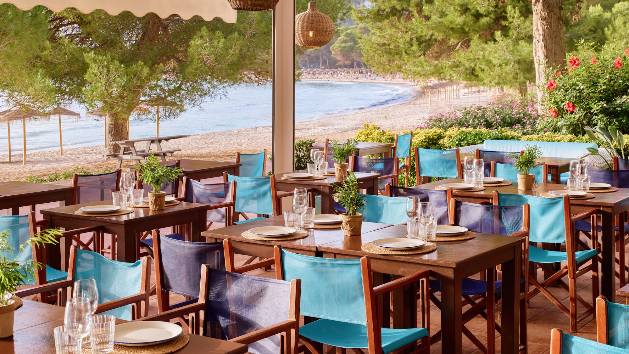 tables and chairs on a patio near a beach