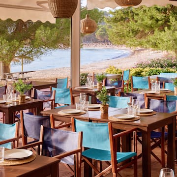 tables and chairs on a patio near a beach