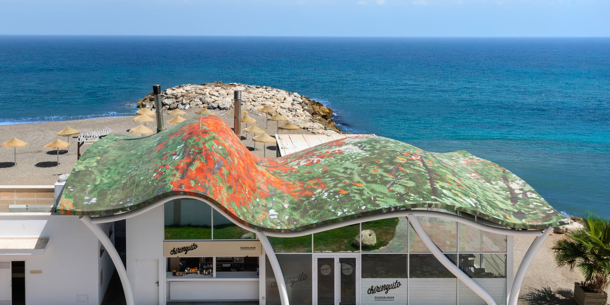 Chiringuito Guadalmar beach bar with wavy, mosaic roof and blue ocean view.