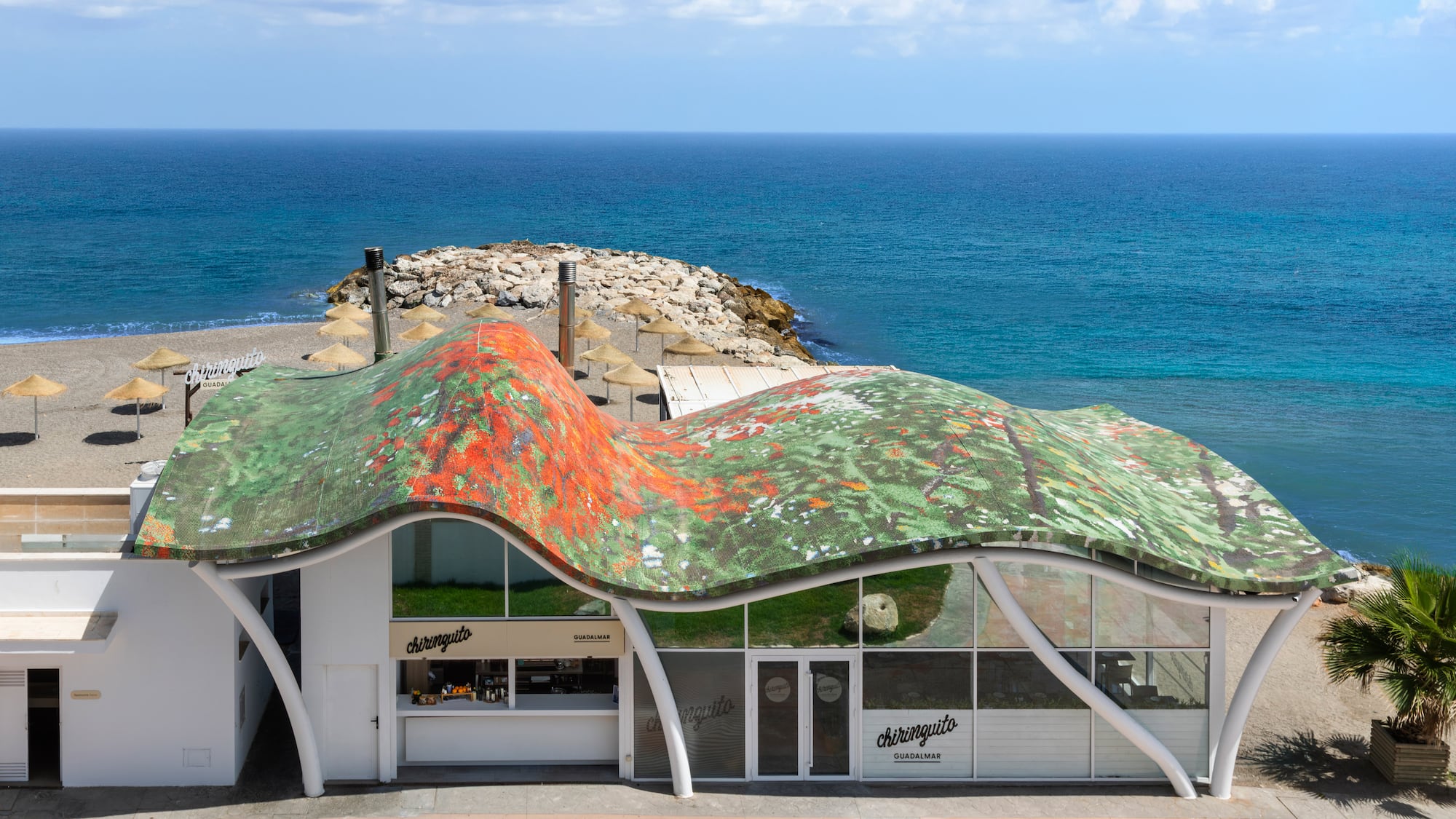 Chiringuito Guadalmar, modern beach bar with wavy colorful roof, sandy beach, ocean.
