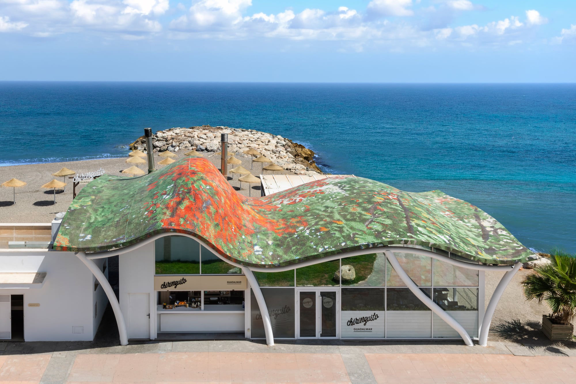 Chiringuito Guadalmar beach bar with wavy, mosaic roof and blue ocean view.