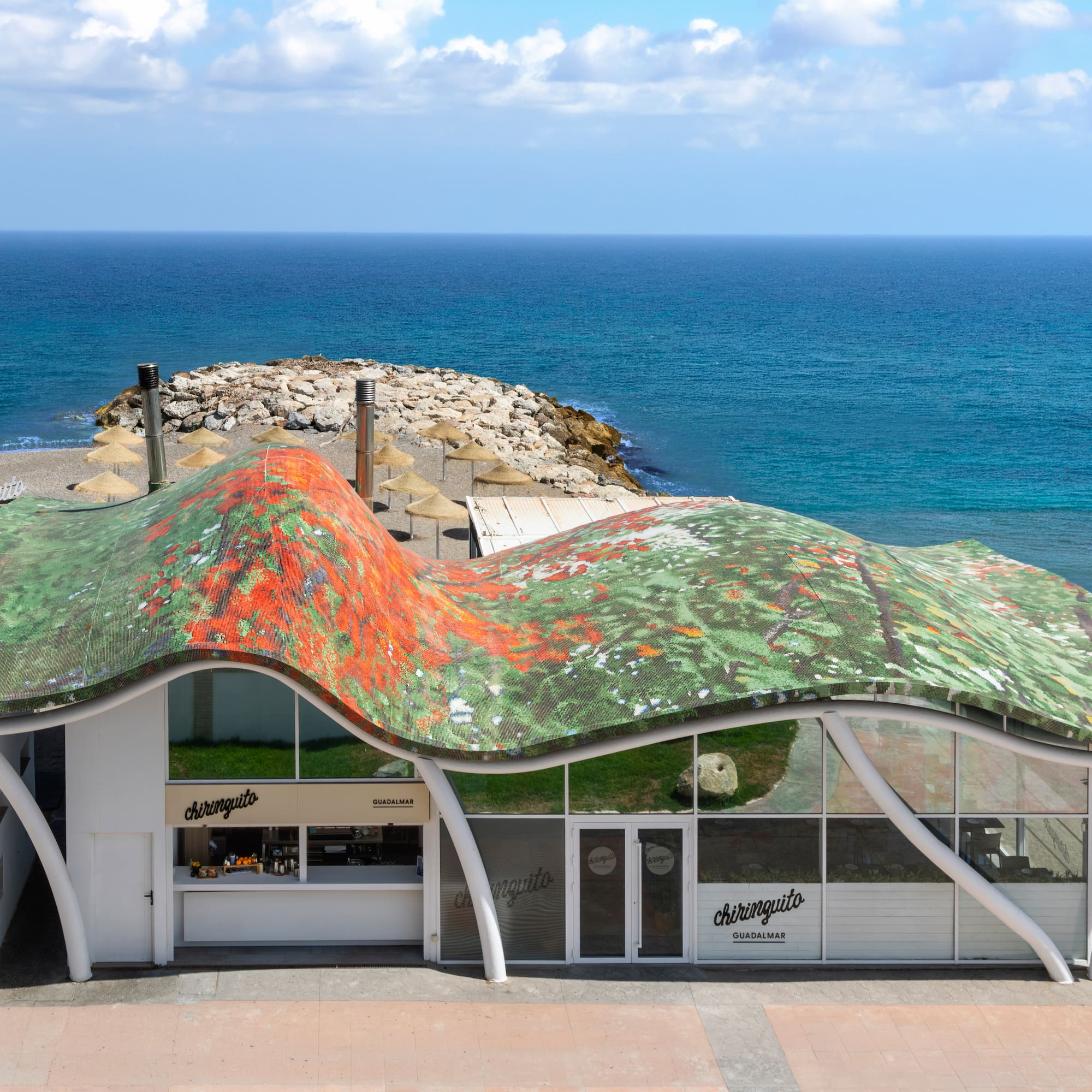 Chiringuito Guadalmar, modern beach bar with wavy colorful roof, sandy beach, ocean.