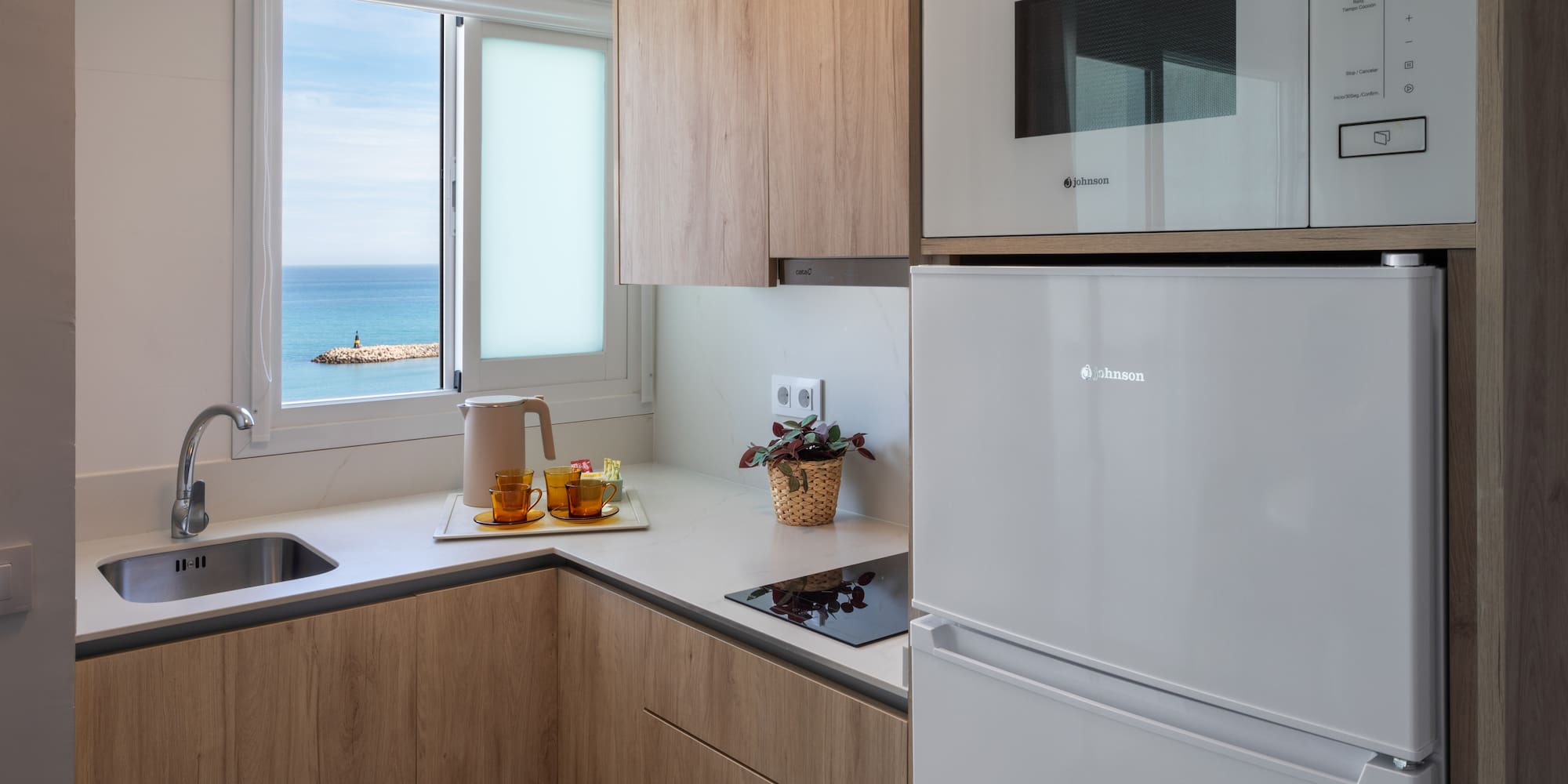 Compact kitchen with ocean view, wooden cabinets, and white appliances.