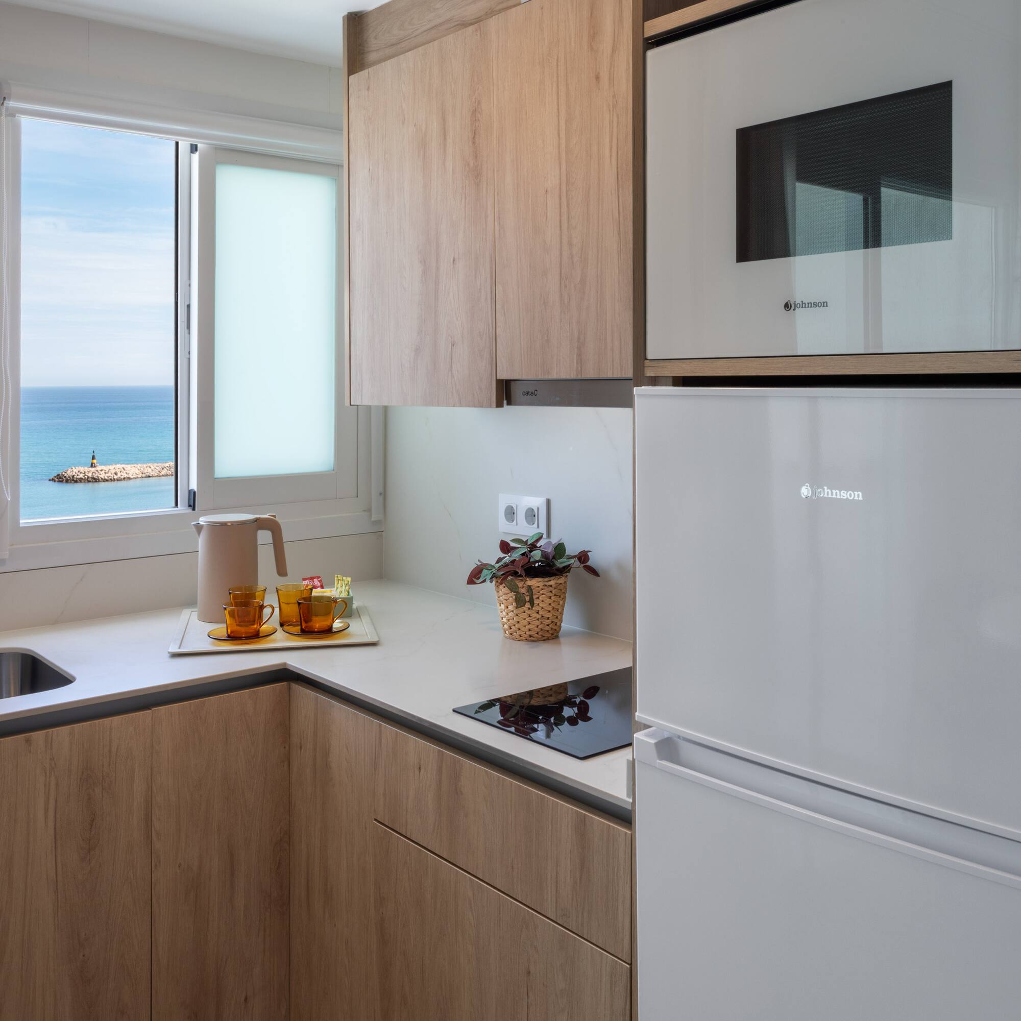 Compact kitchen with ocean view, wooden cabinets, and white appliances.