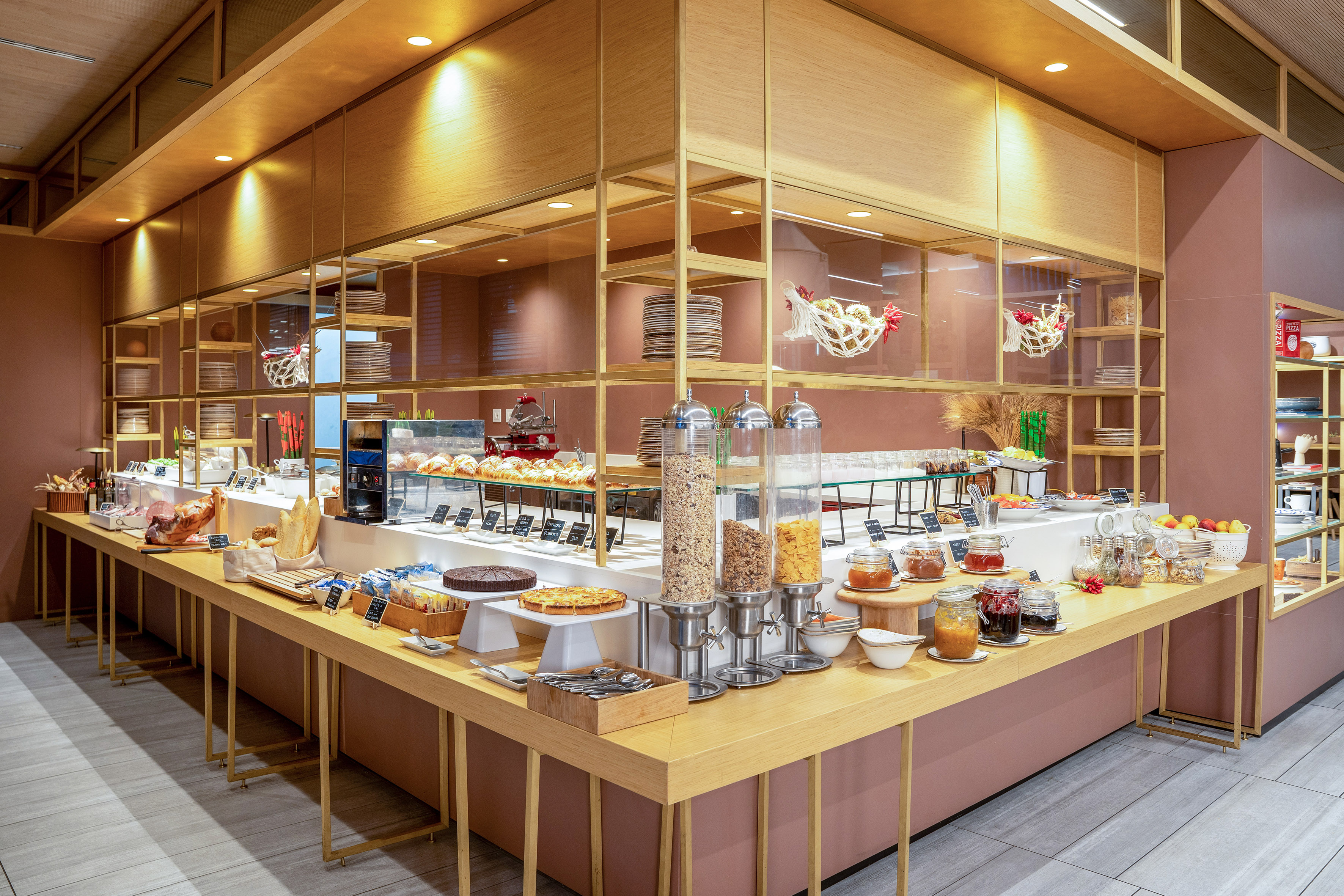 Modern breakfast buffet with pastries, cereals, jams, fruits, and cold cuts.
