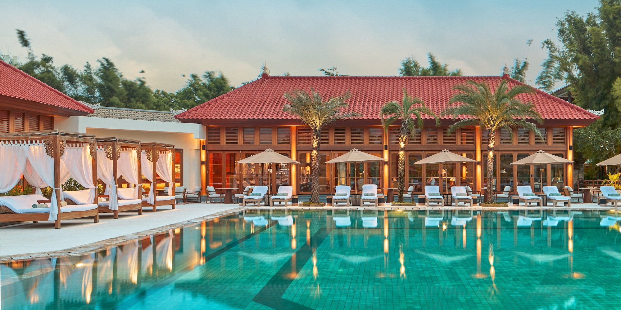 a pool with chairs and umbrellas in front of a building