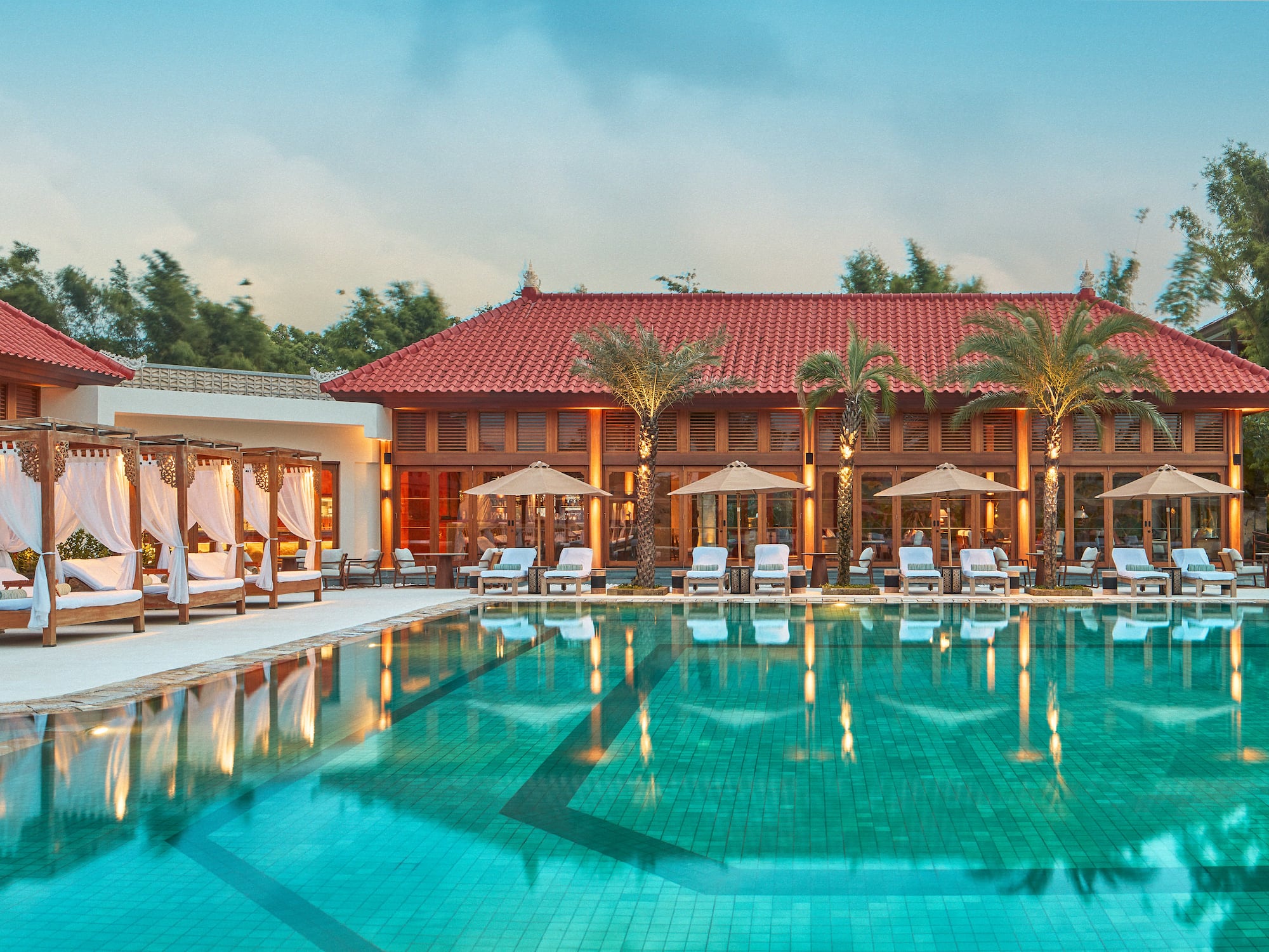 a pool with chairs and umbrellas in front of a building