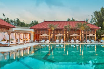 a pool with chairs and umbrellas in front of a building