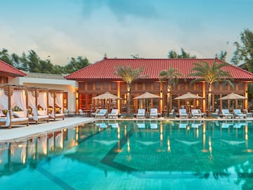 a pool with chairs and umbrellas in front of a building