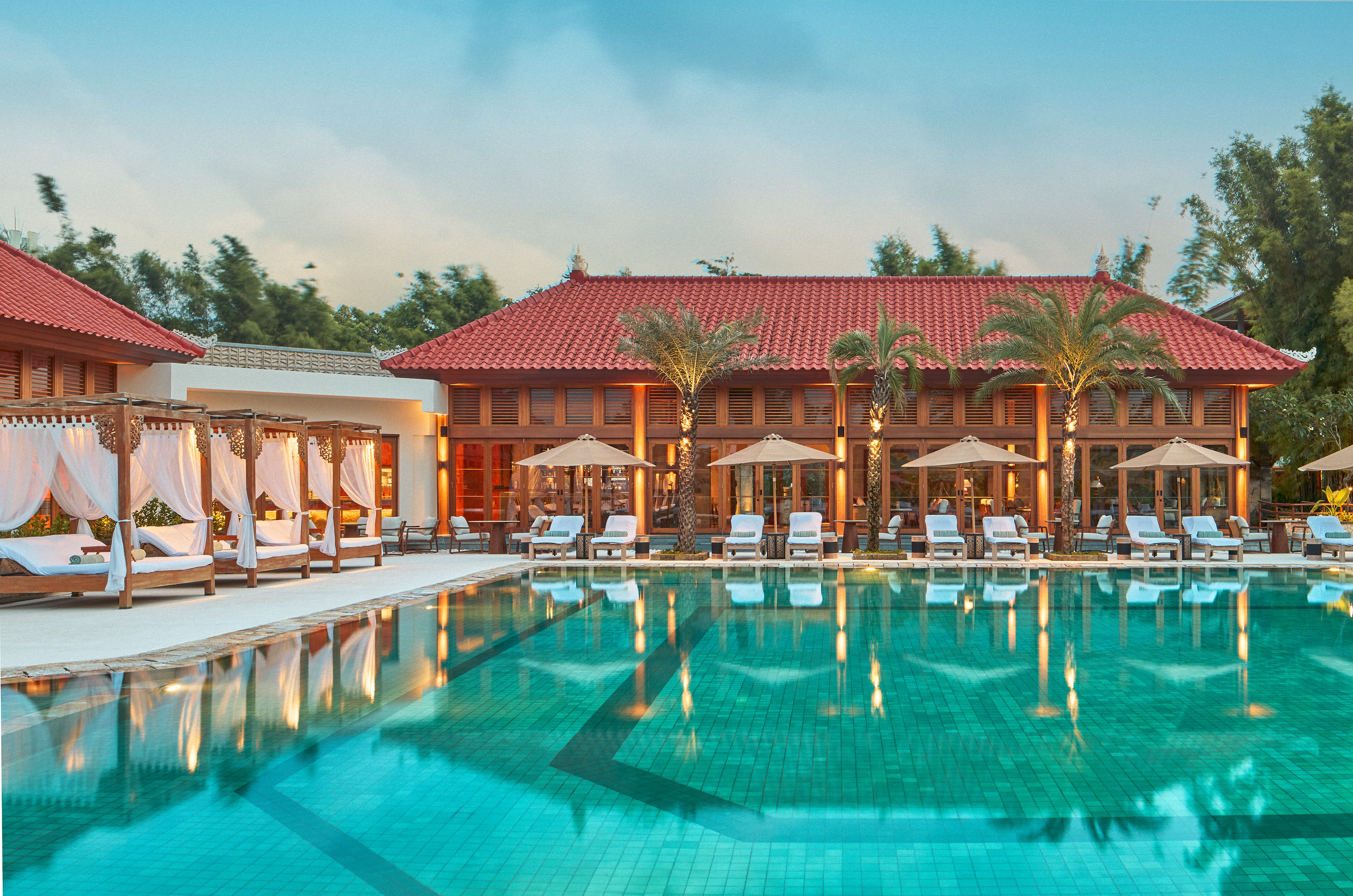 a pool with chairs and umbrellas in front of a building