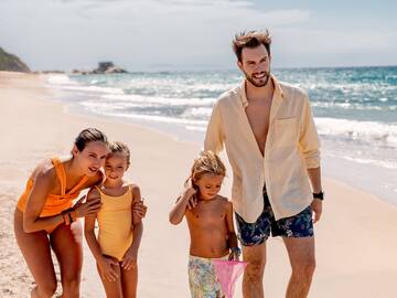 a man and woman walking on a beach with children