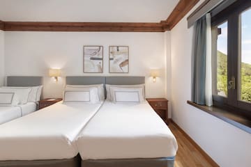 a bed with white sheets and lamps